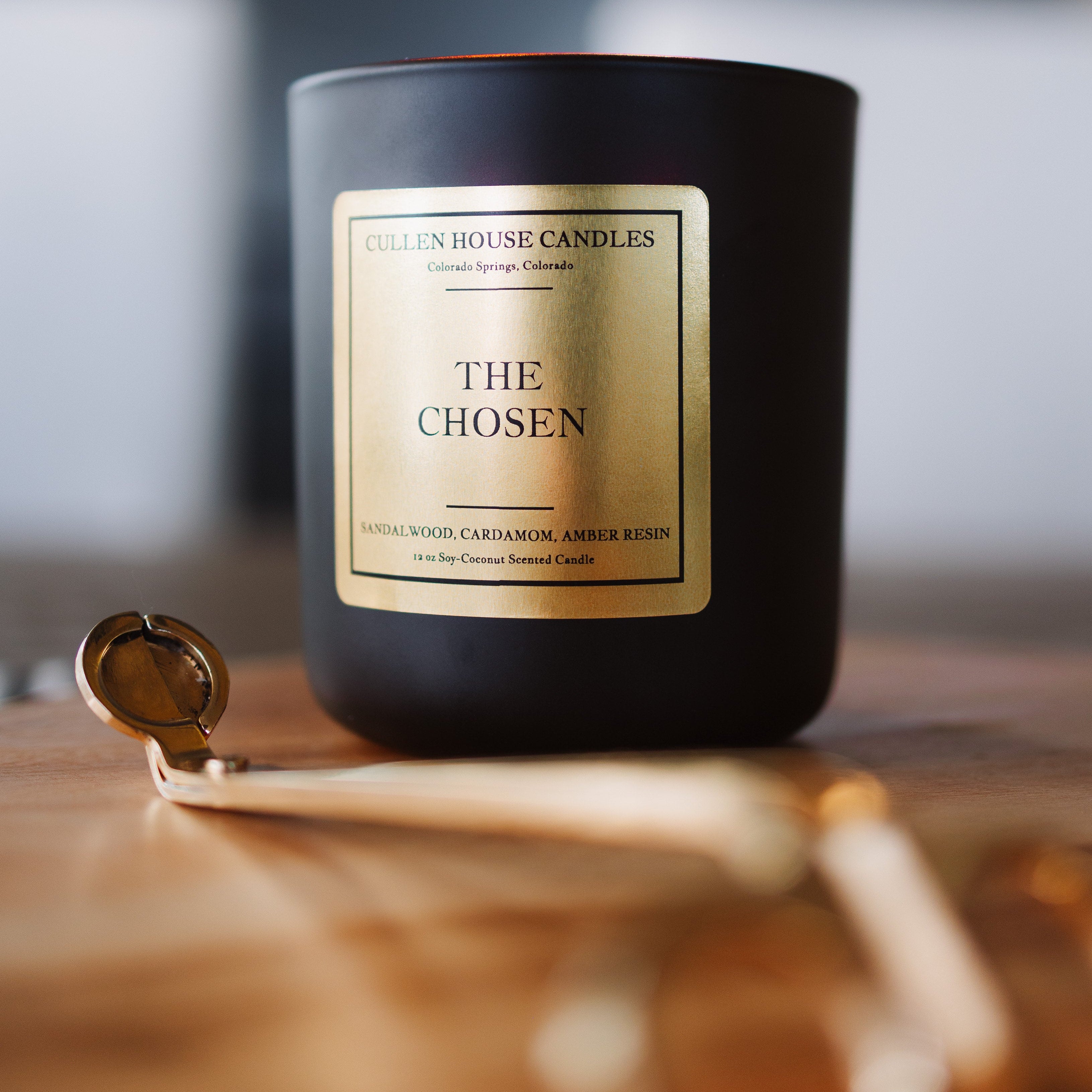 Black candle labeled 'The Chosen' on a wooden surface with a blurred background