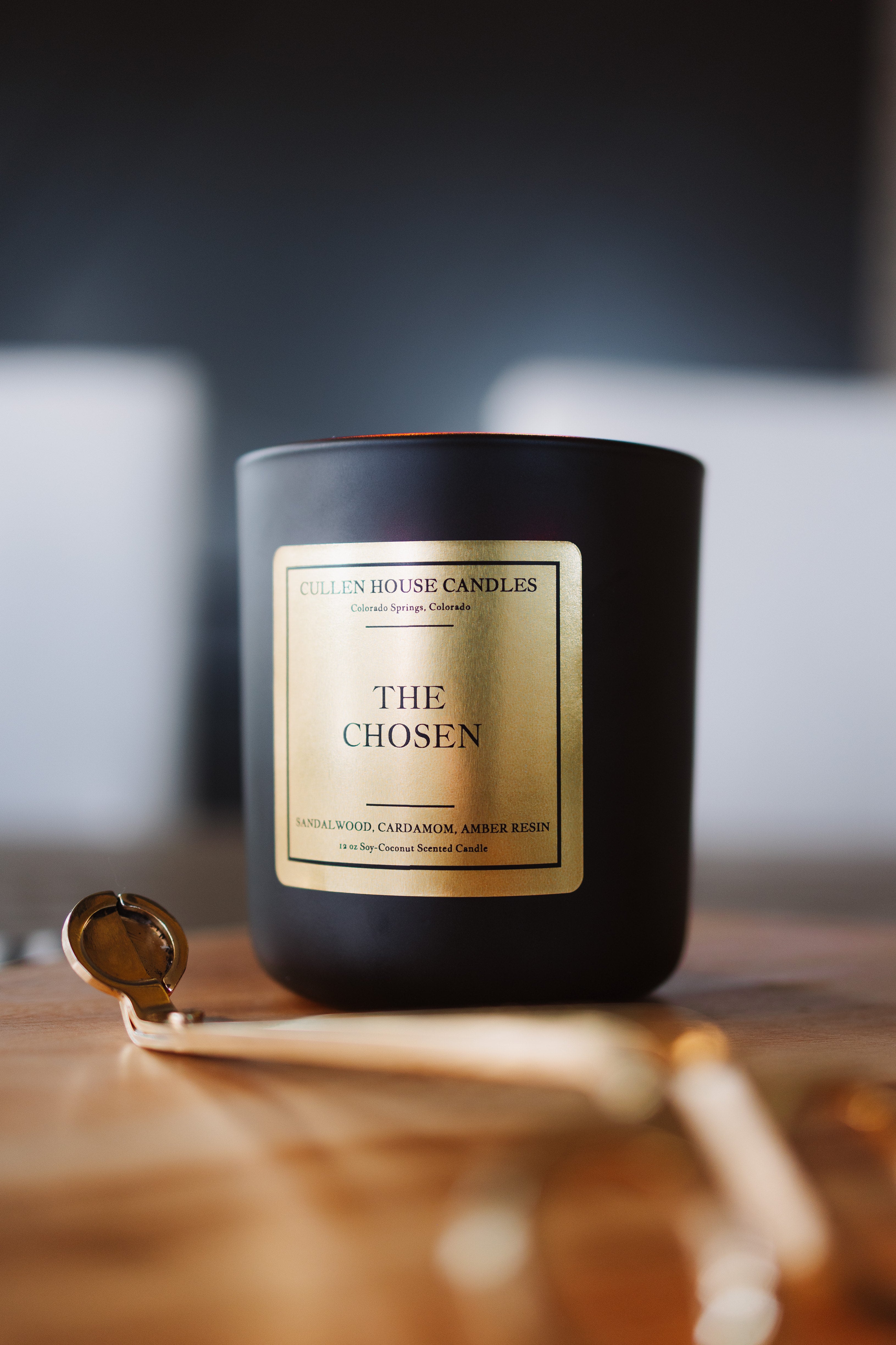 Black candle labeled 'The Chosen' on a wooden surface with a blurred background