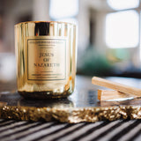 Gold candle labeled 'Jesus of Nazareth' on a decorative tray with blurred background