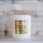 White candle with a gold label on a blurred background