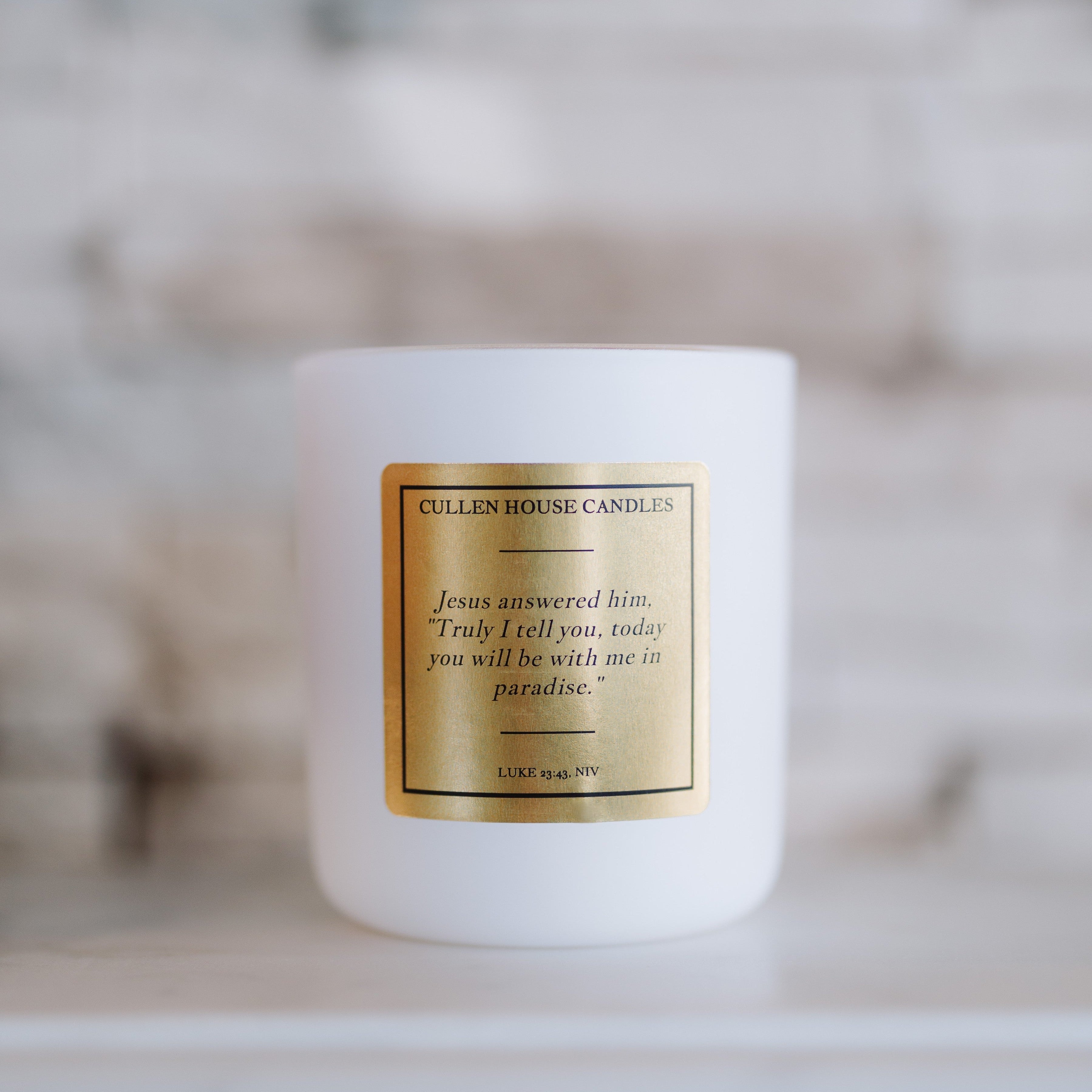White candle with a gold label on a blurred background