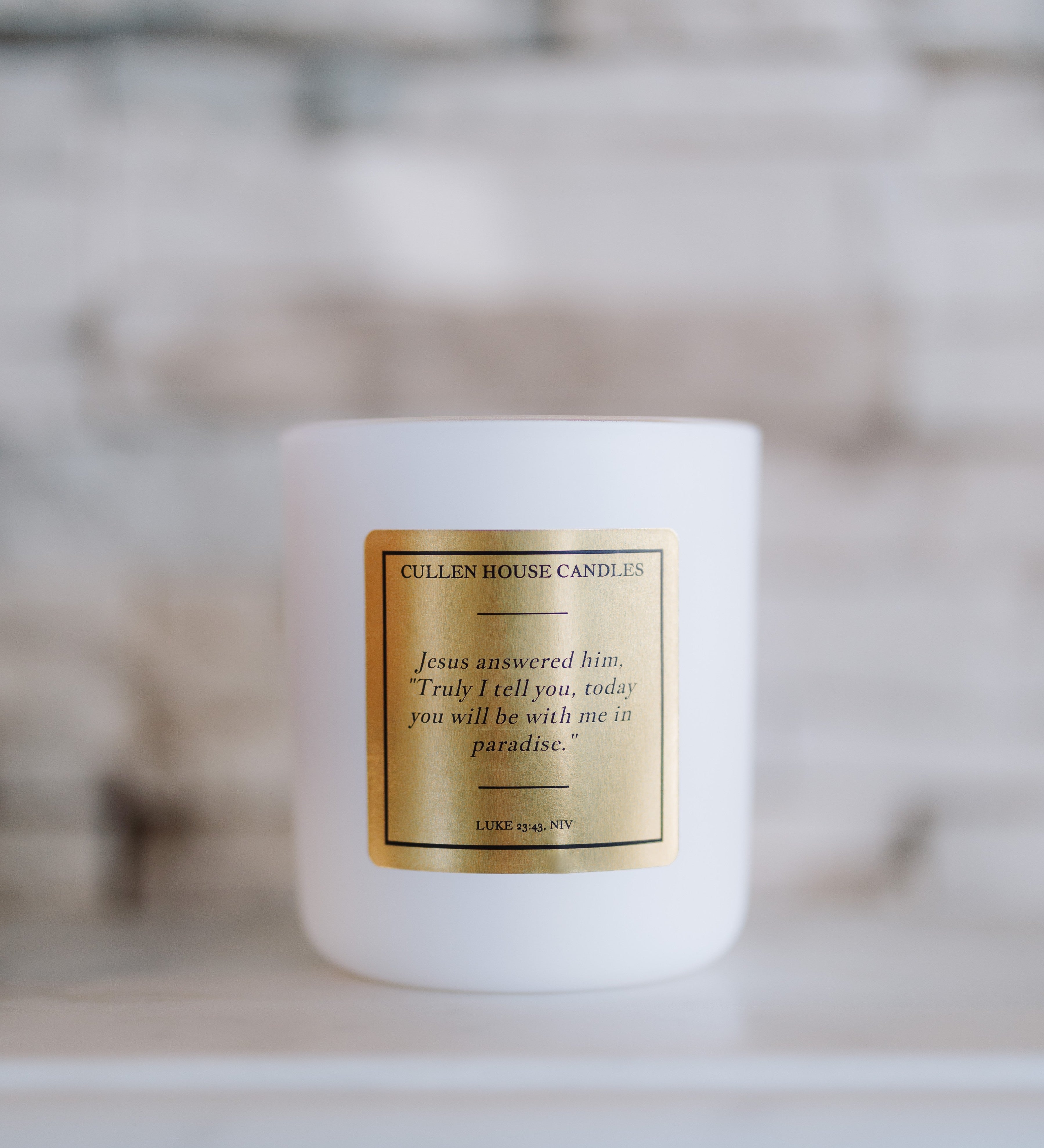 White candle with a gold label on a blurred background