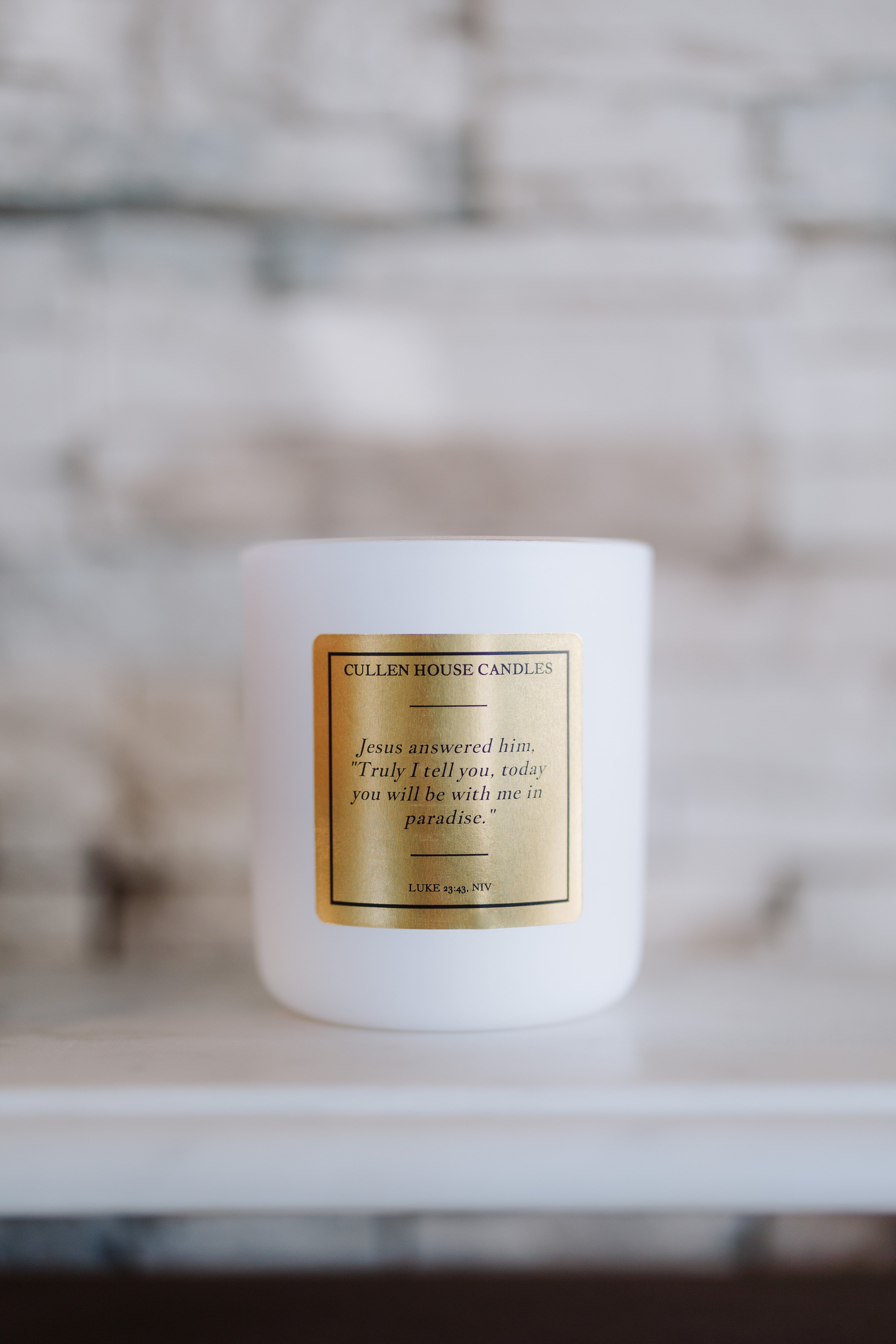 White candle with a gold label on a blurred background