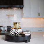 Decorative items on a black round stand in a kitchen setting