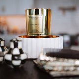 Candle with gold packaging on a decorative stand in a home setting