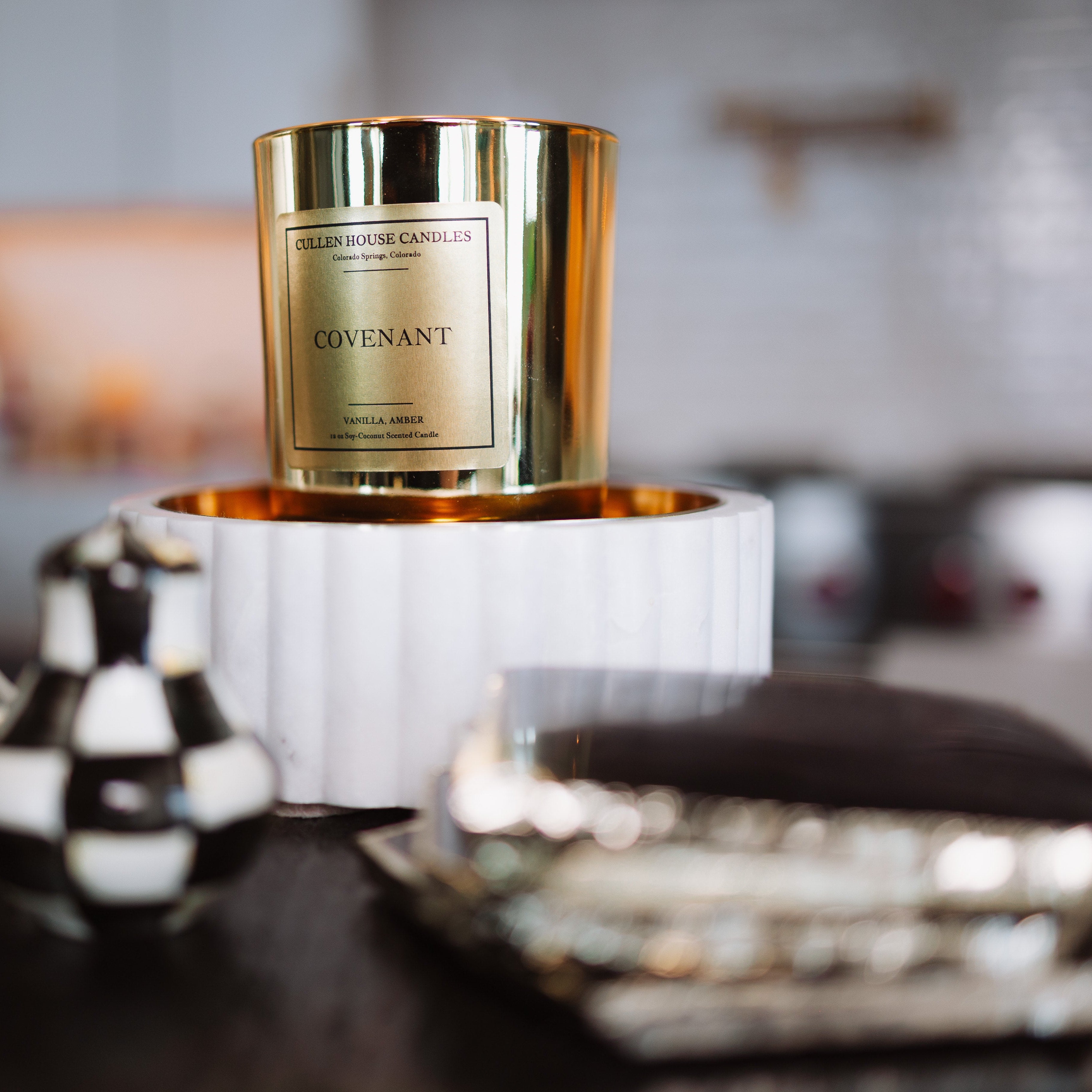 Candle with gold packaging on a decorative stand in a home setting