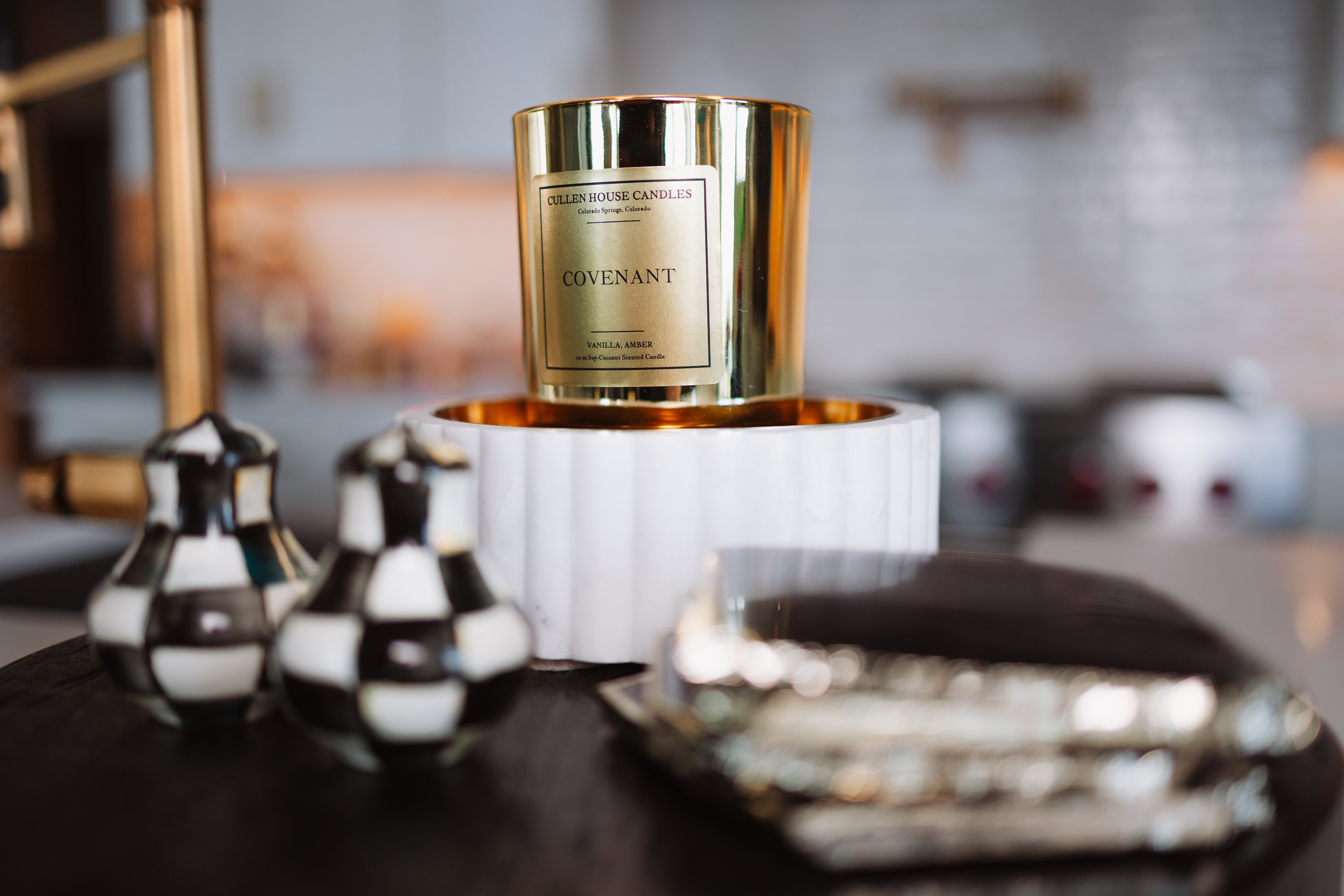 Candle with gold packaging on a decorative stand in a home setting