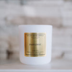 Candle with 'Paradise' label on a white surface