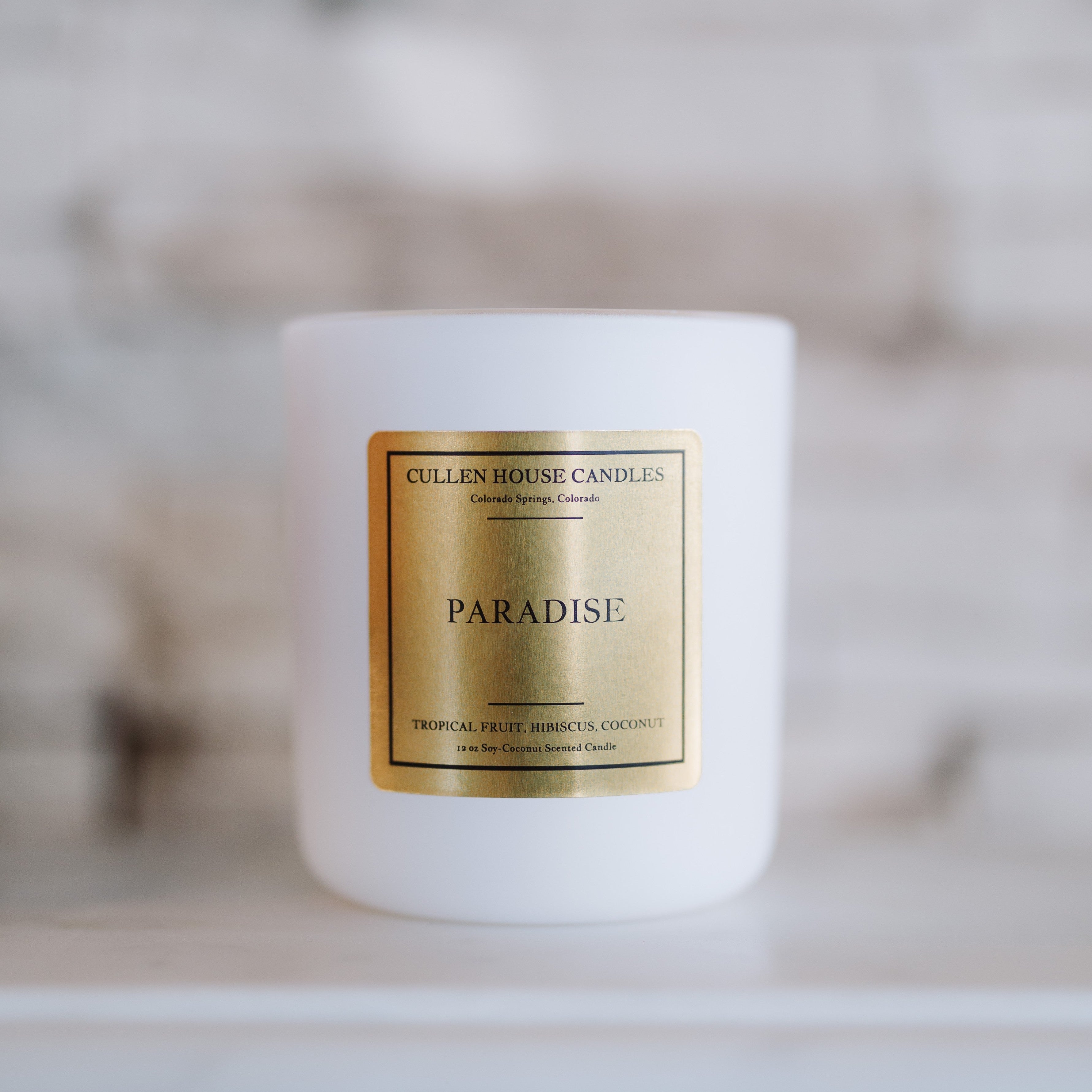 Candle with 'Paradise' label on a white surface
