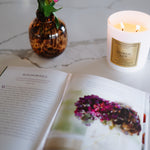Open book with a candle and vase of flowers on a marble surface