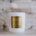 White candle with a gold label on a marble surface