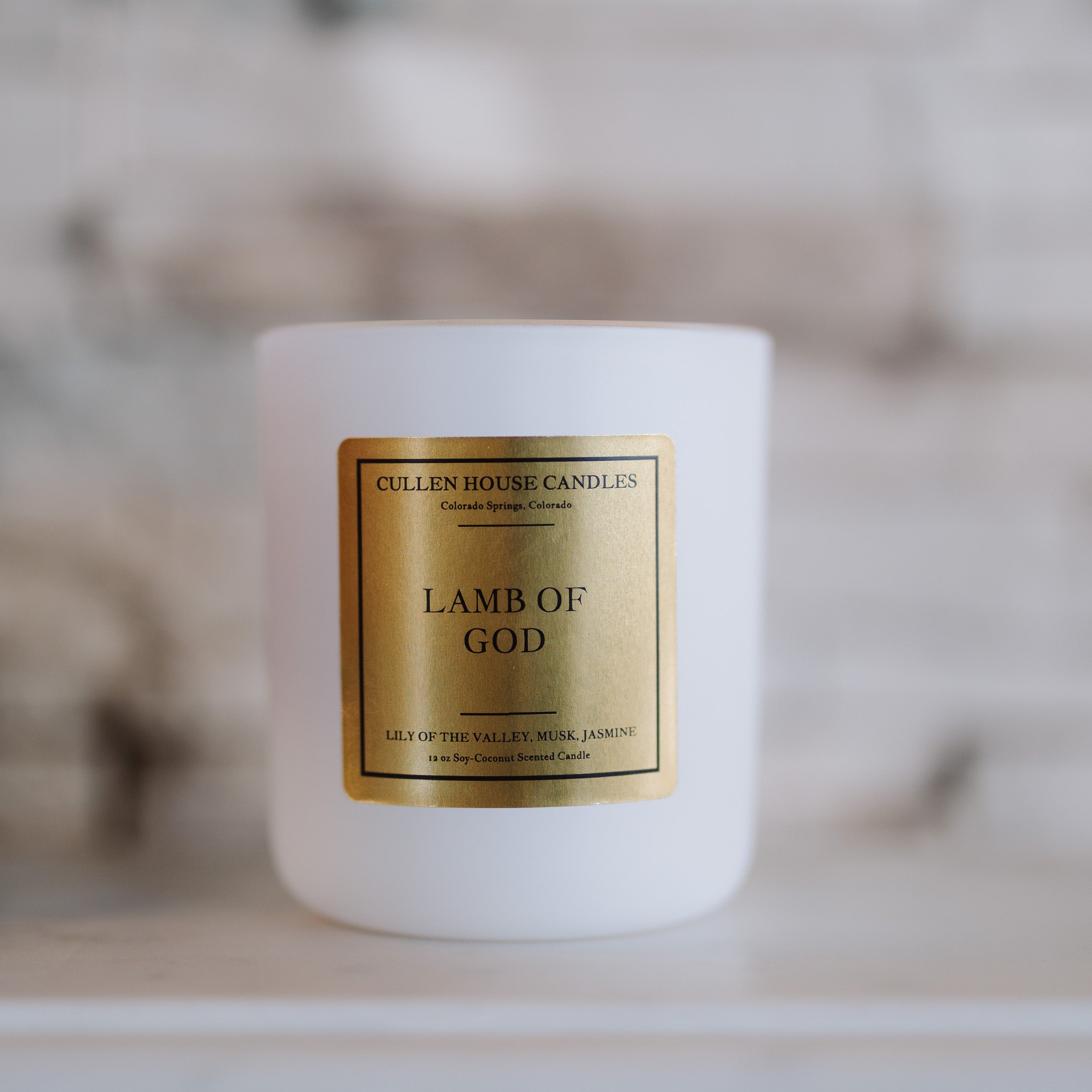White candle with a gold label on a marble surface