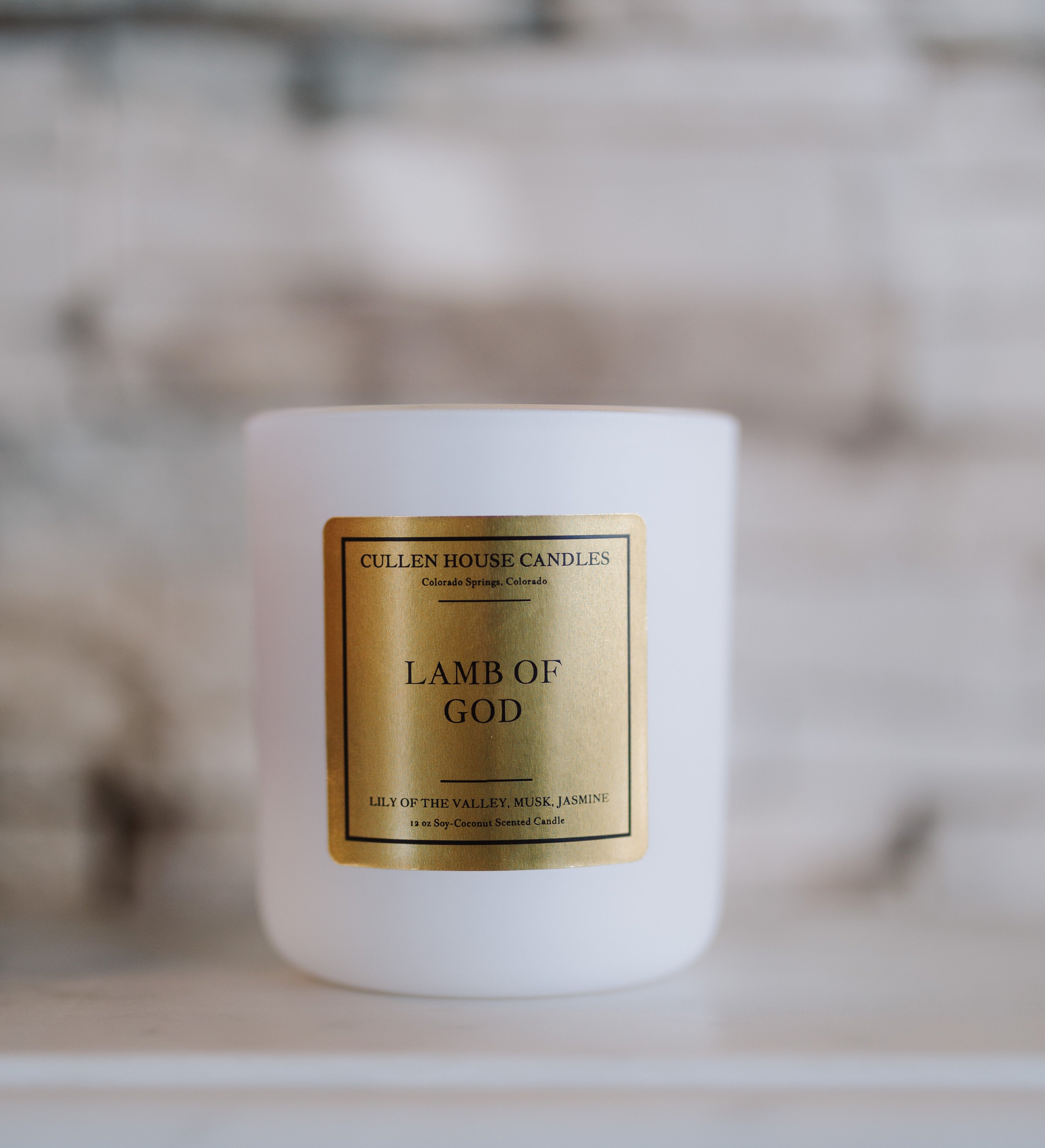 White candle with a gold label on a marble surface