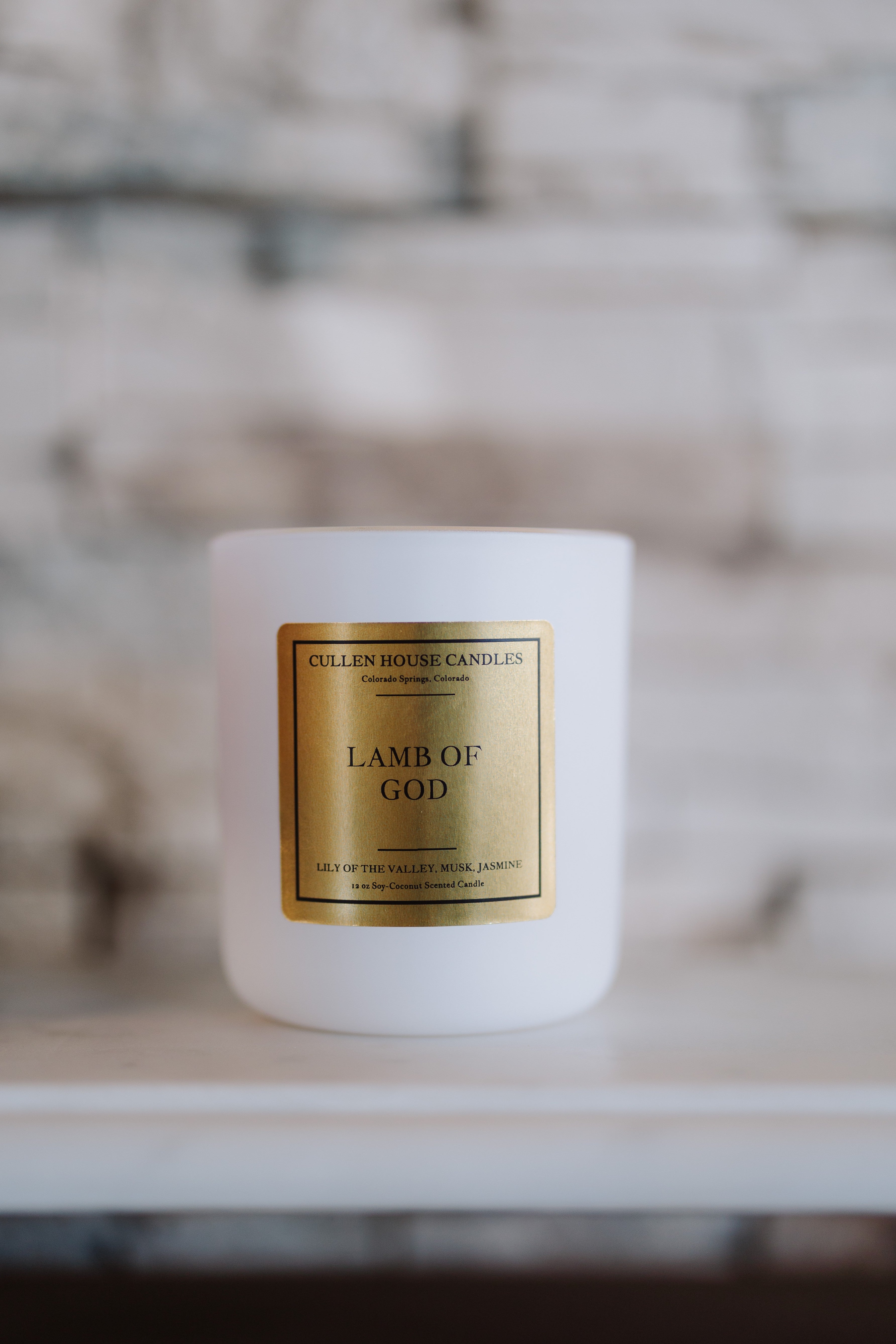 White candle with a gold label on a marble surface