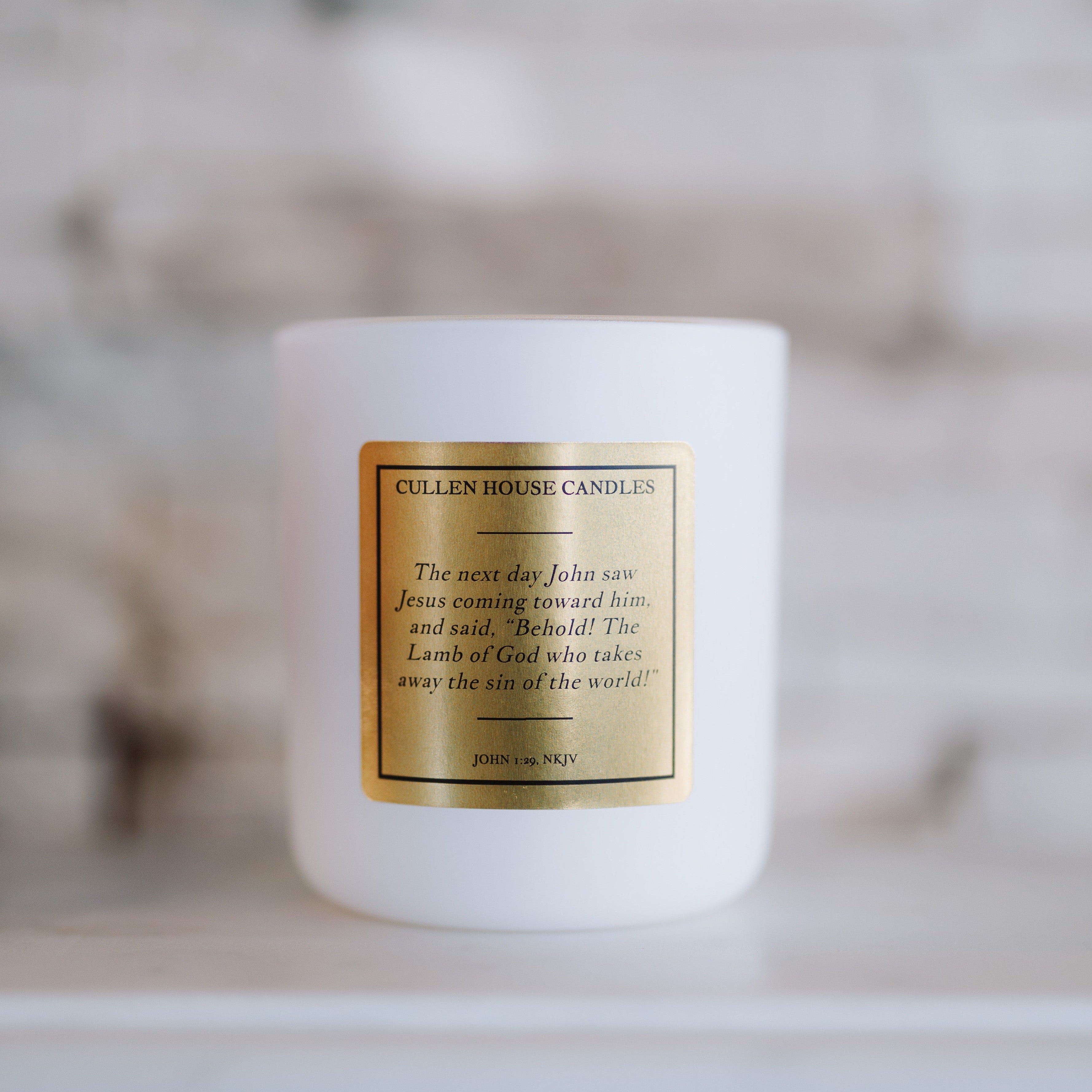 White candle with a gold label on a blurred background