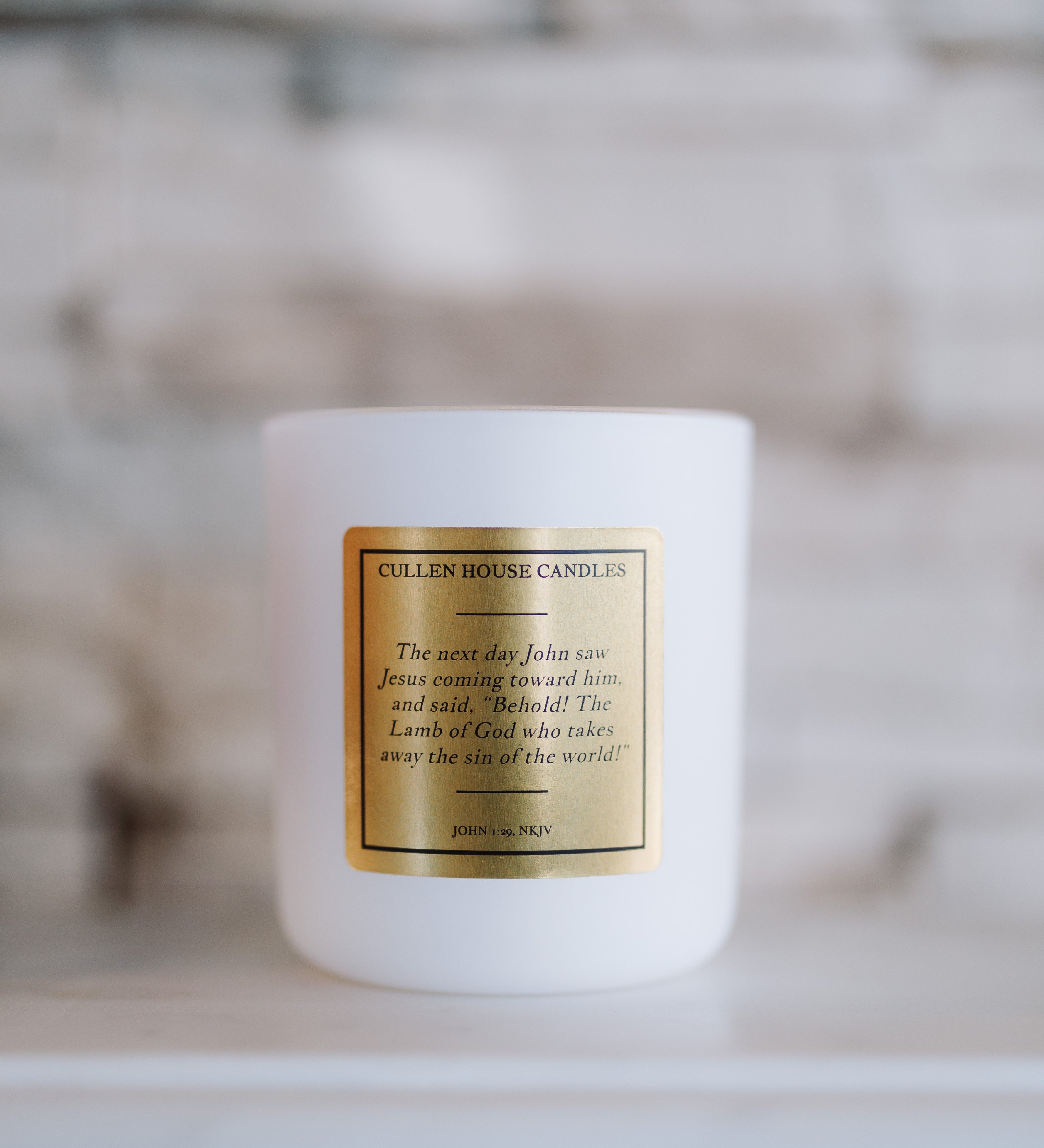 White candle with a gold label on a blurred background