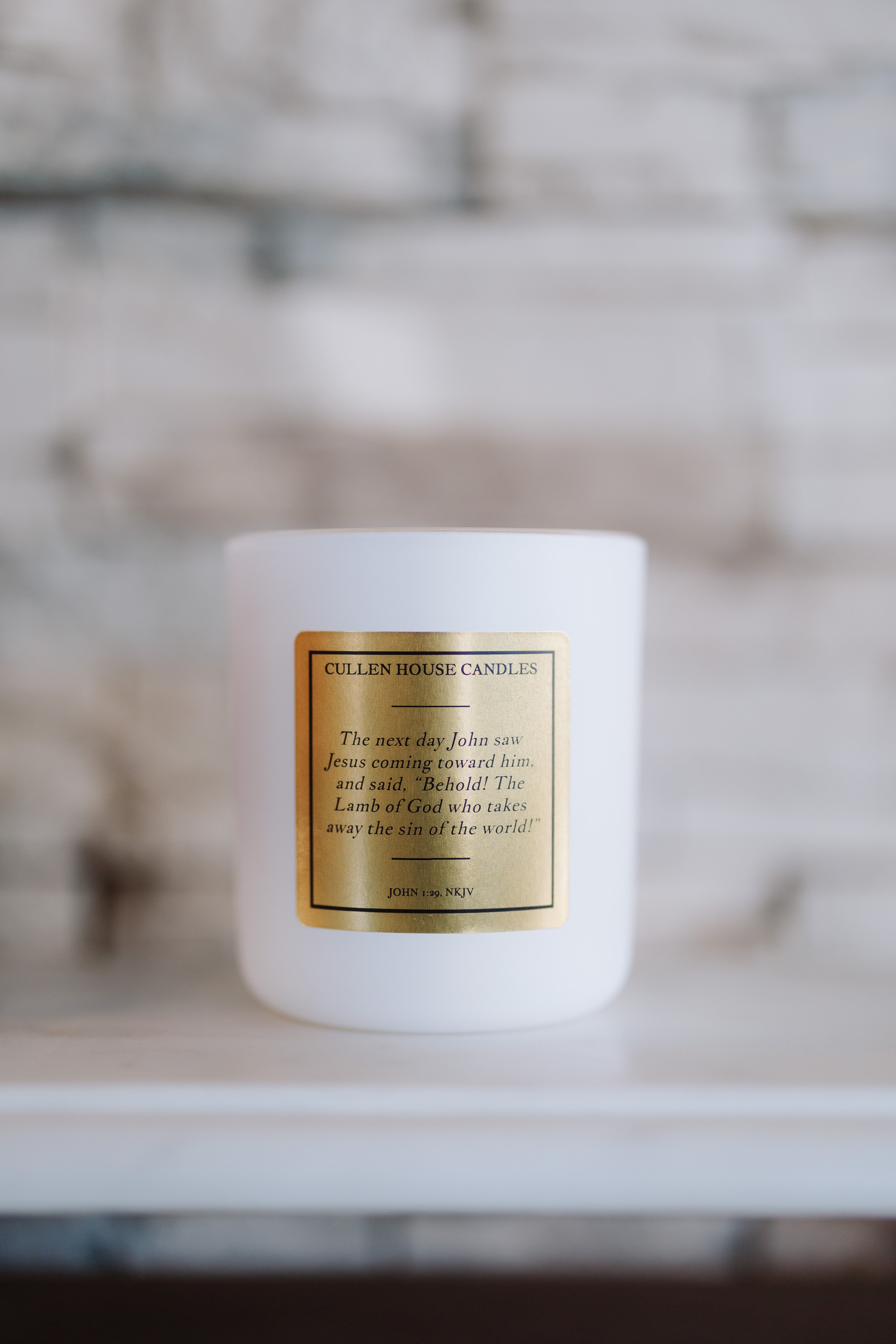 White candle with a gold label on a blurred background