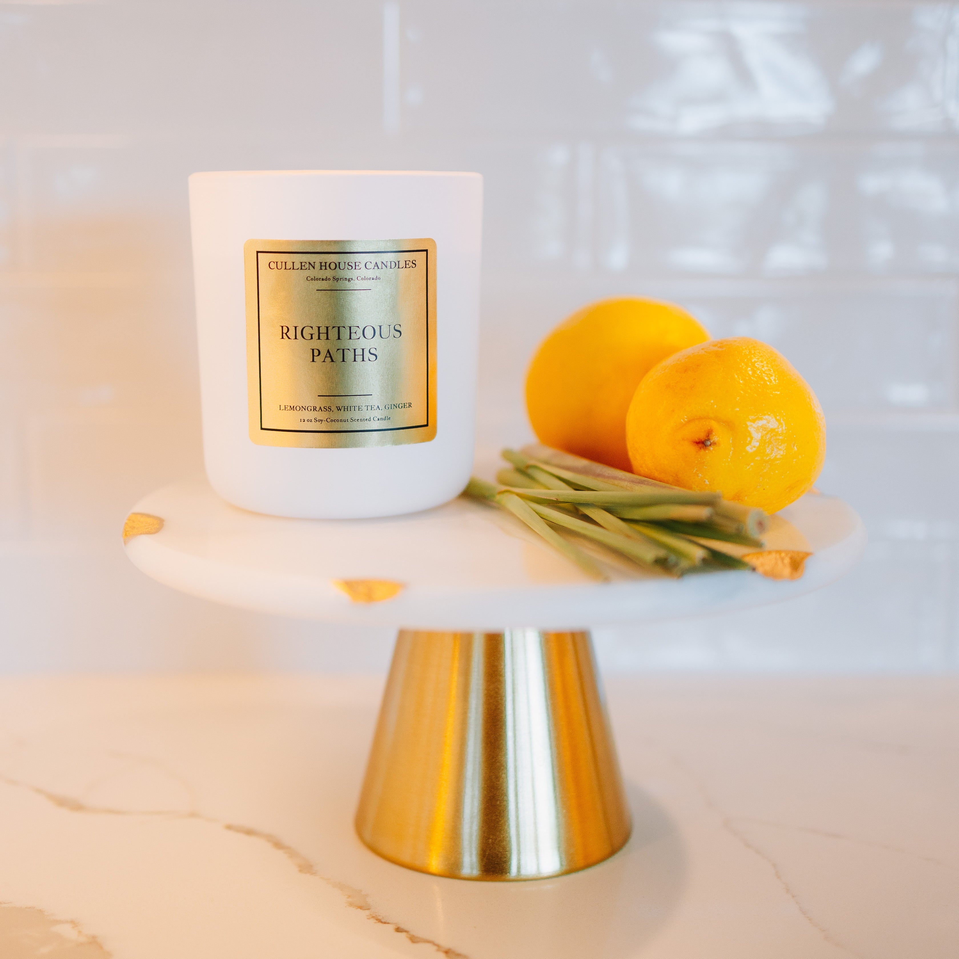 Candle on a white pedestal with lemons on a marble surface