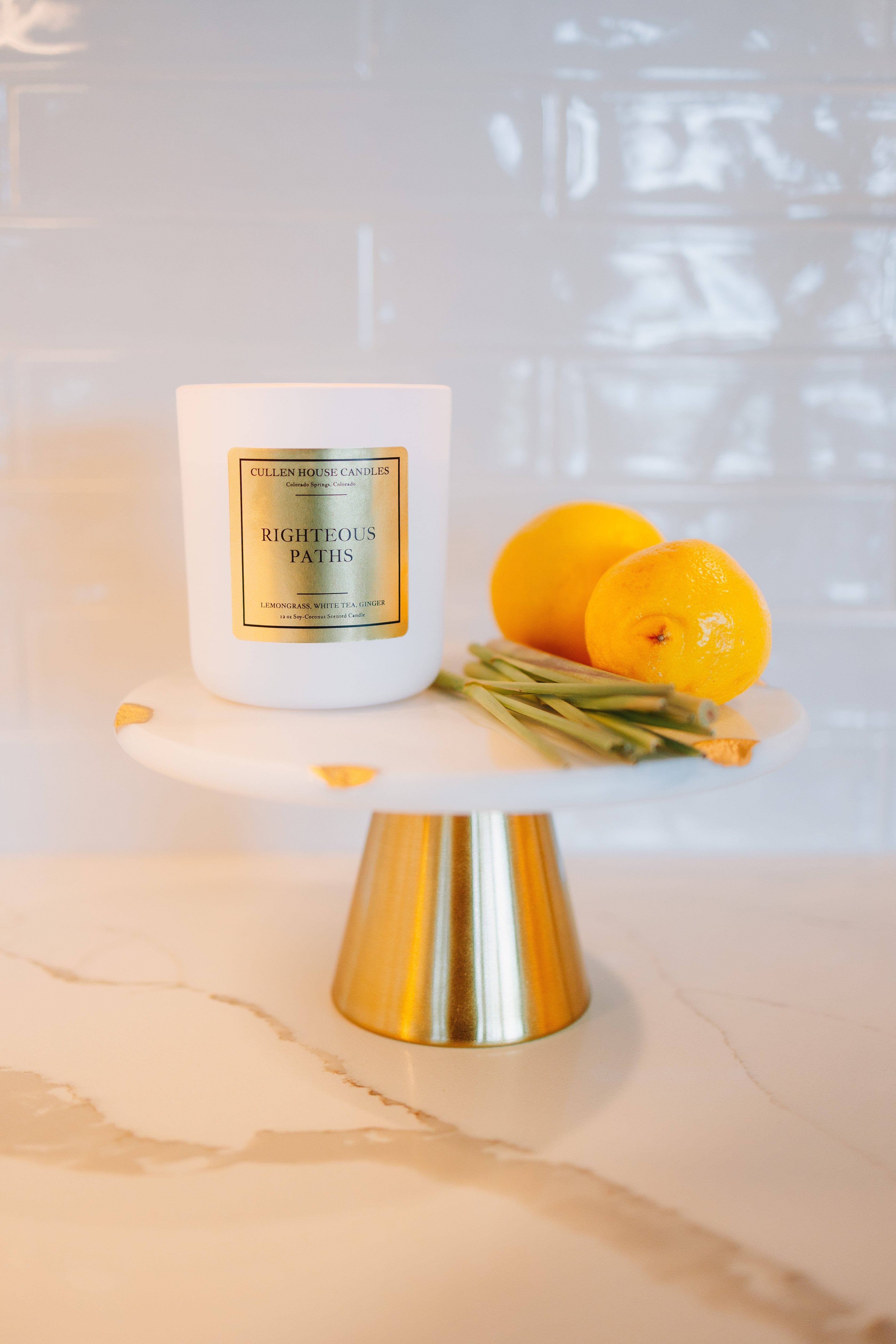 Candle on a white pedestal with lemons on a marble surface