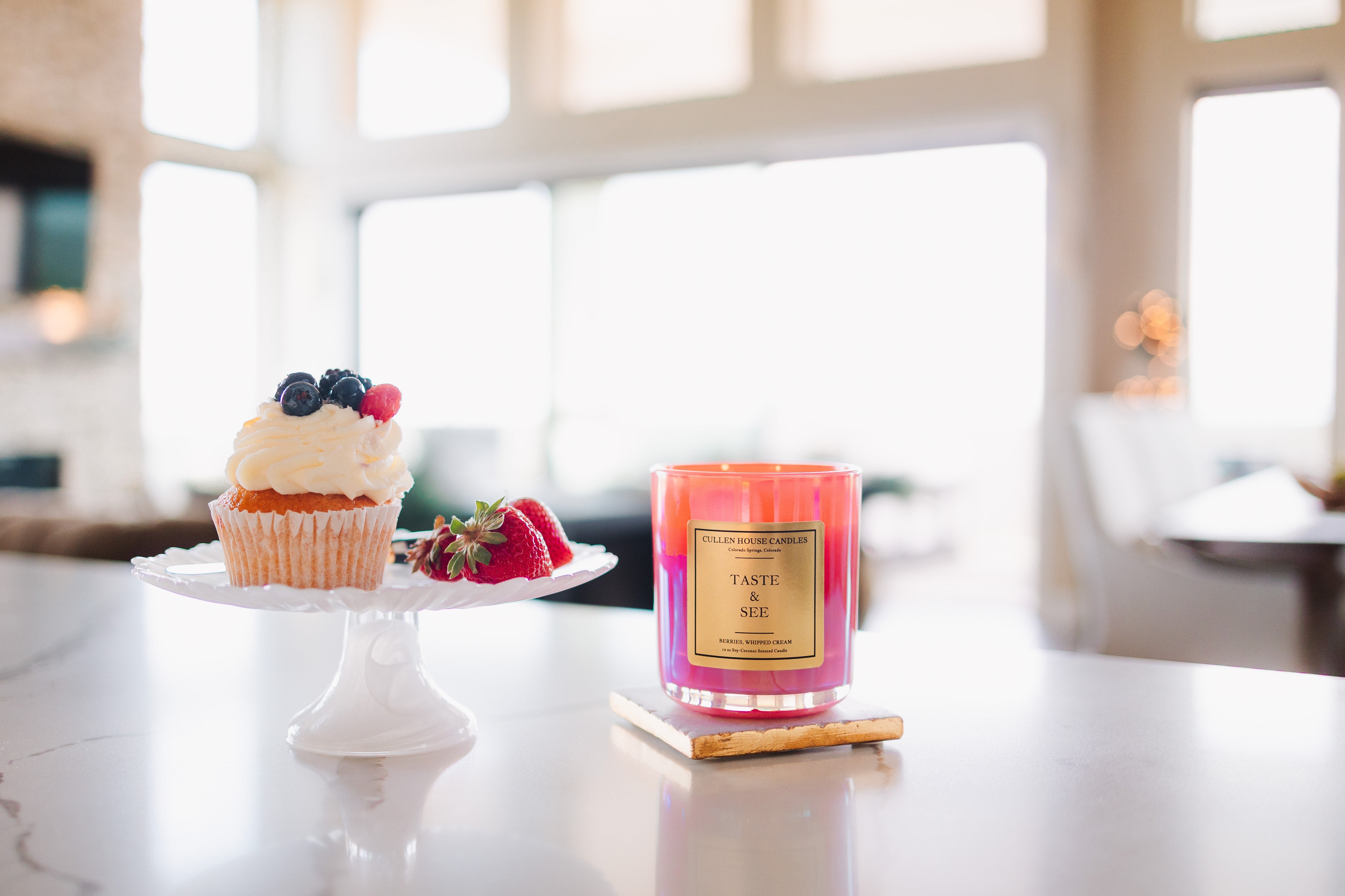 Candle labeled 'Taste the Rainbow' on a table with a cake and fruit in the background