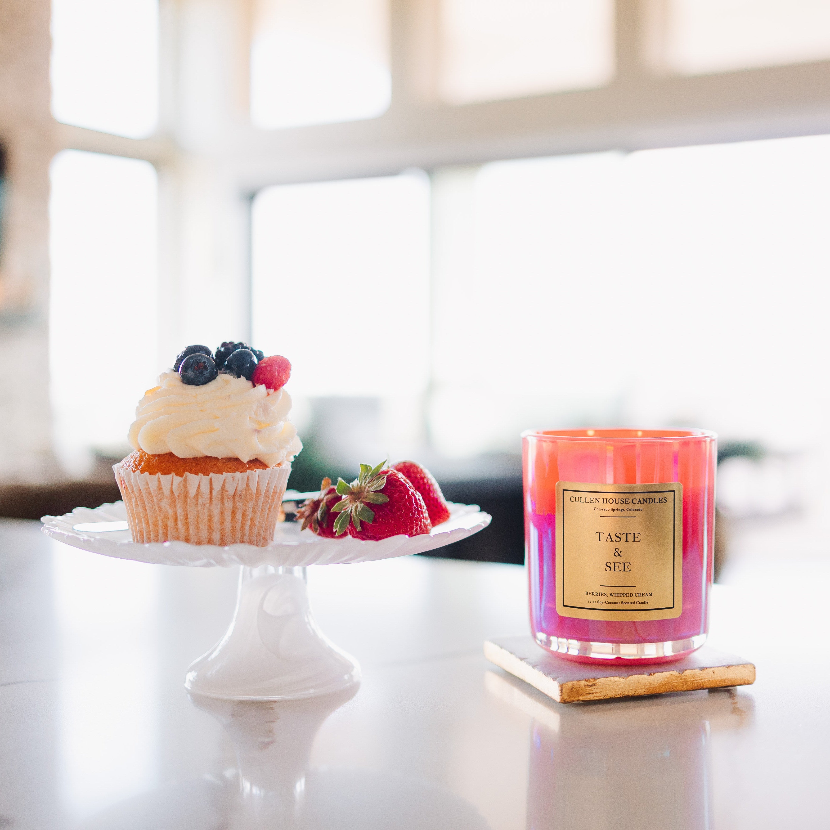 Candle labeled 'Taste the Rainbow' on a table with a cake and fruit in the background