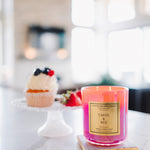 Pink candle labeled 'Taste & See' on a kitchen counter with a blurred background