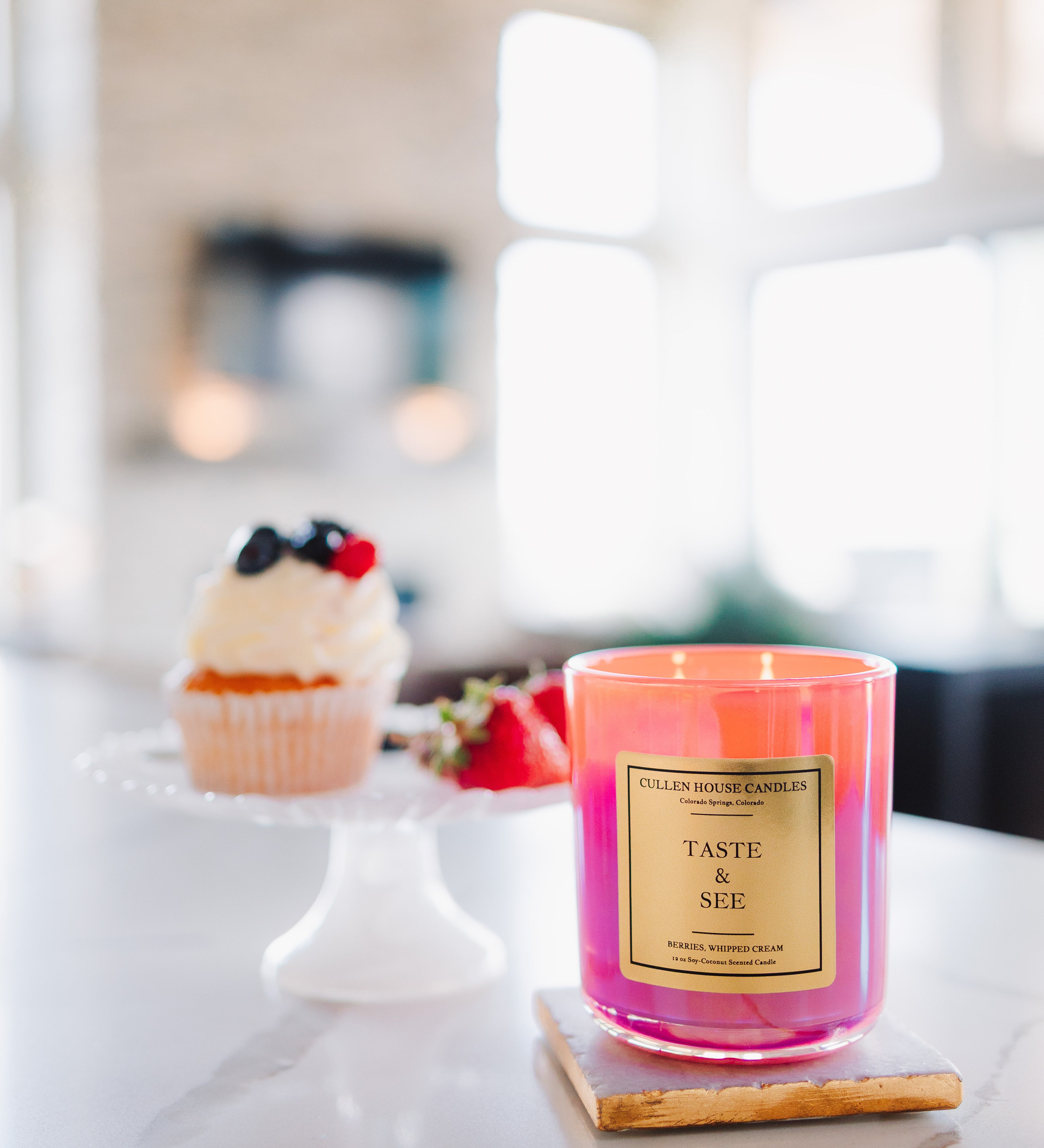 Pink candle labeled 'Taste & See' on a kitchen counter with a blurred background