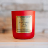 Red candle with a gold label on a wooden surface