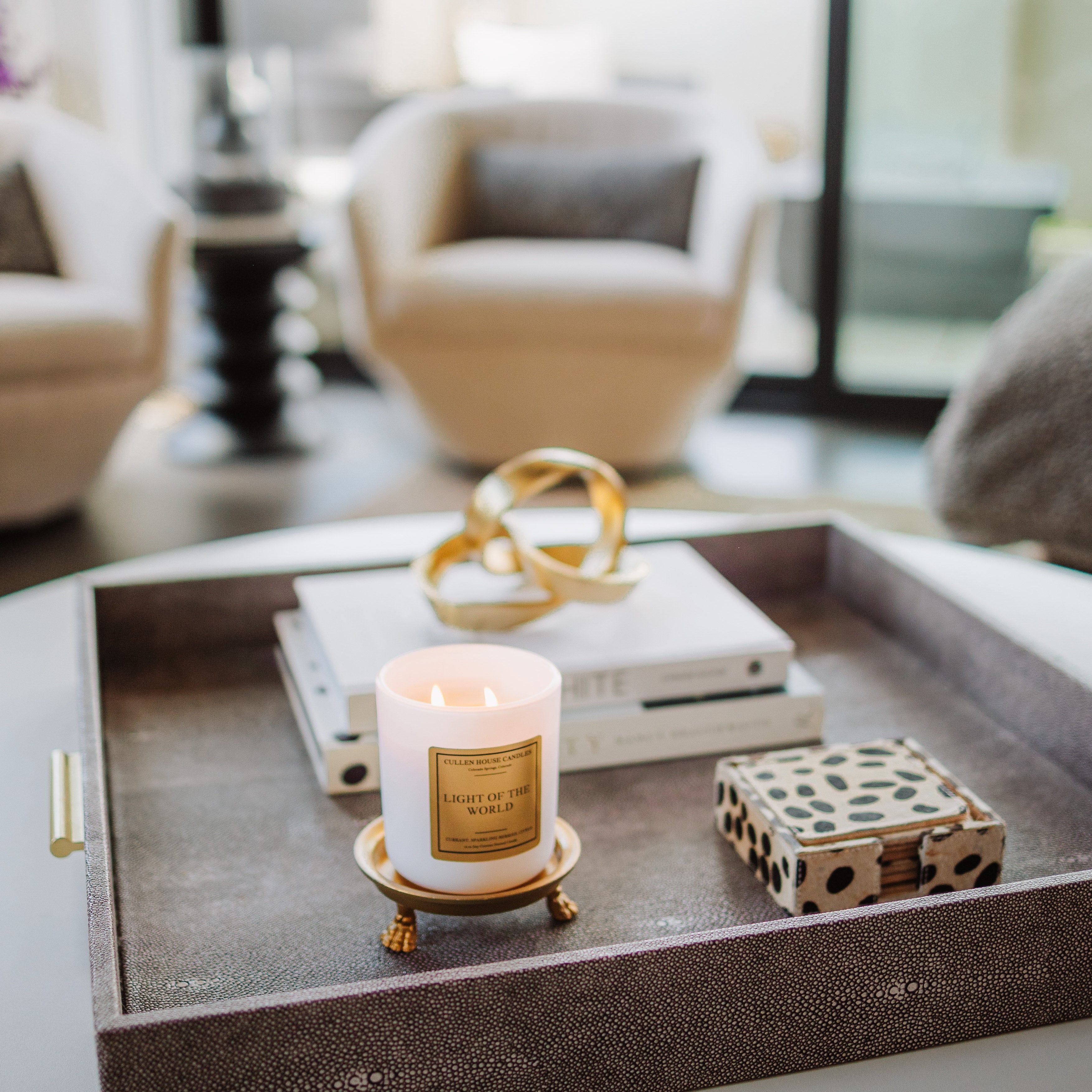 Decorative tray with a candle, book, and decorative item on a coffee table in a living room.