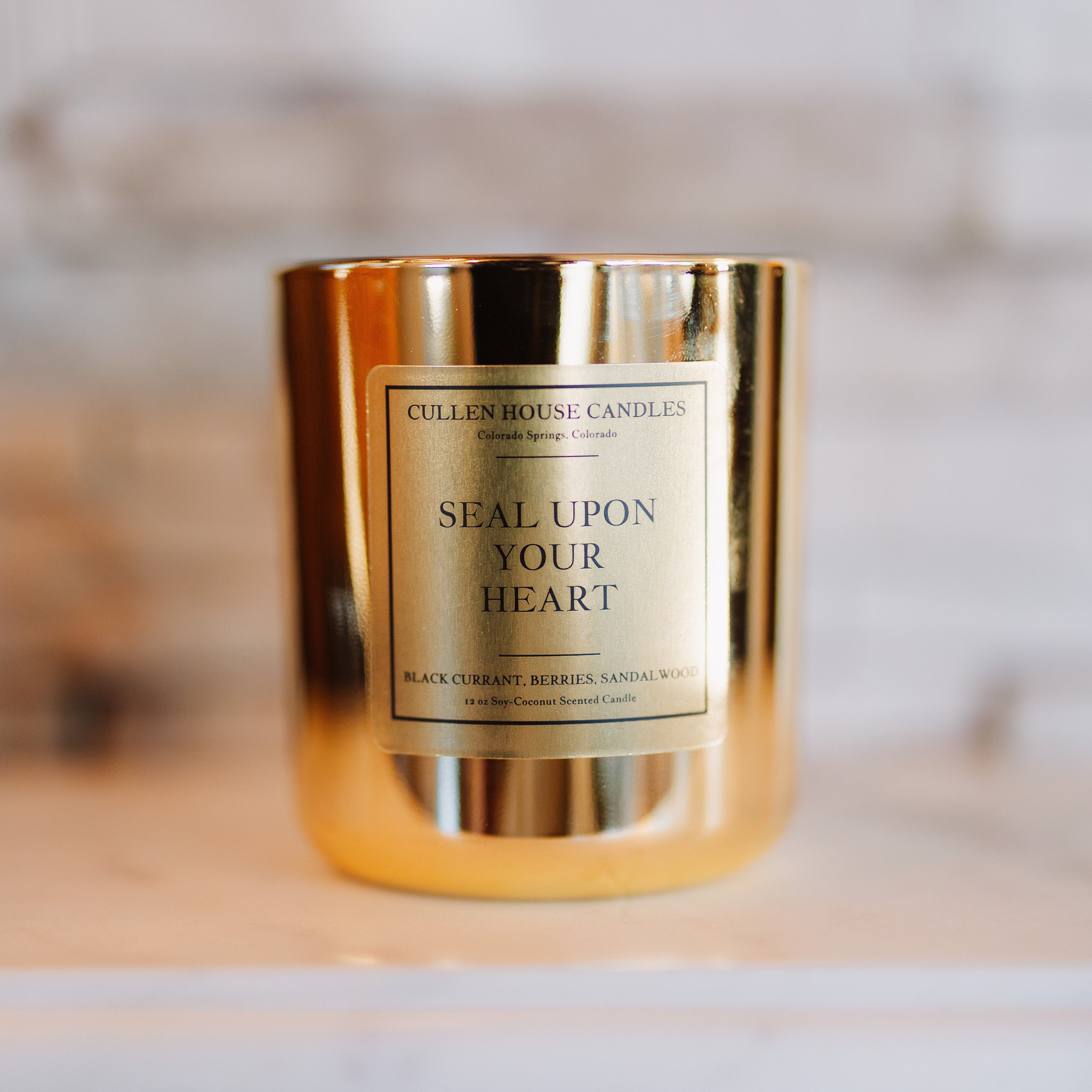 Gold candle with a label on a wooden surface