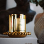 Gold candle with 'Cullen & Co.' branding on a white surface with a blurred background