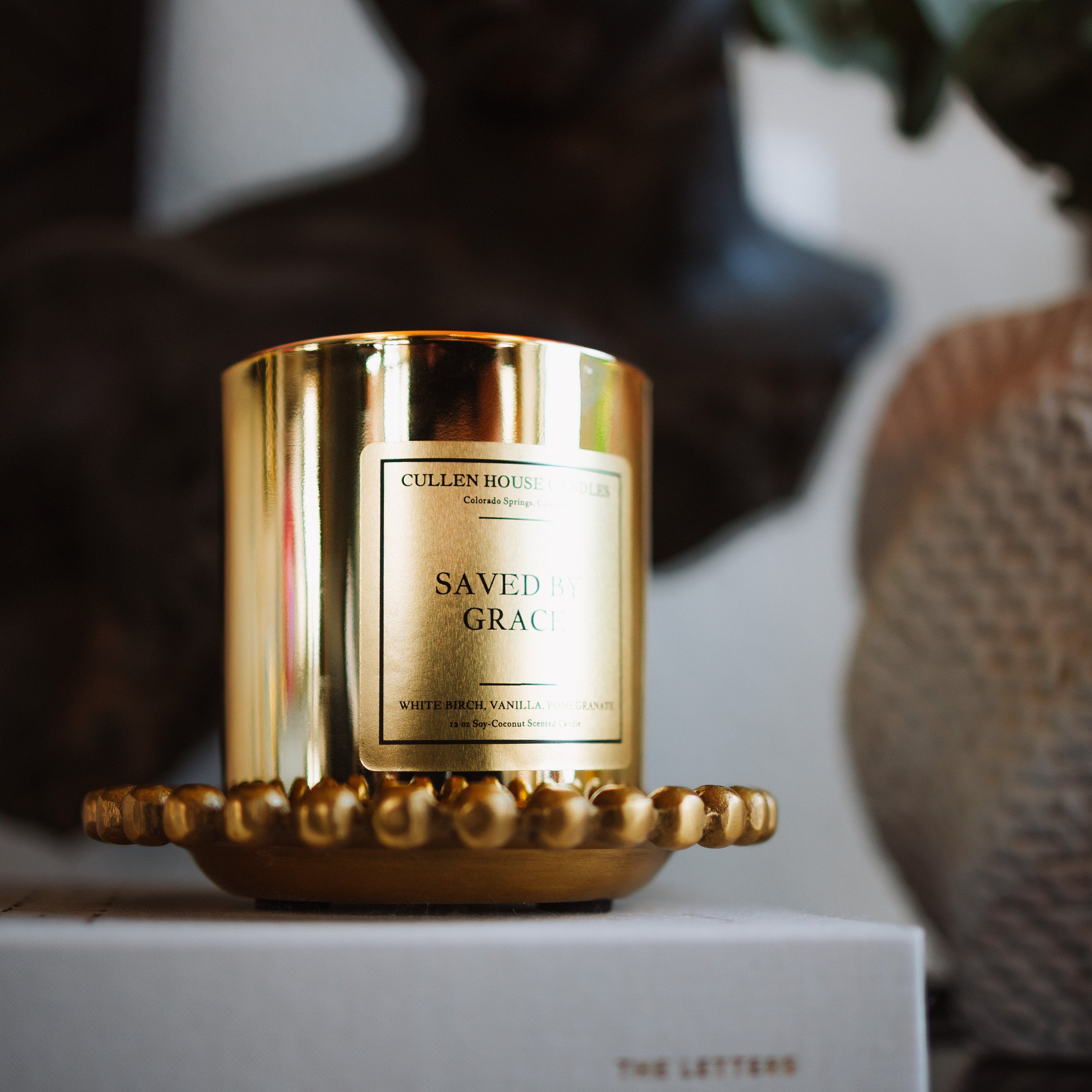 Gold candle with 'Cullen & Co.' branding on a white surface with a blurred background