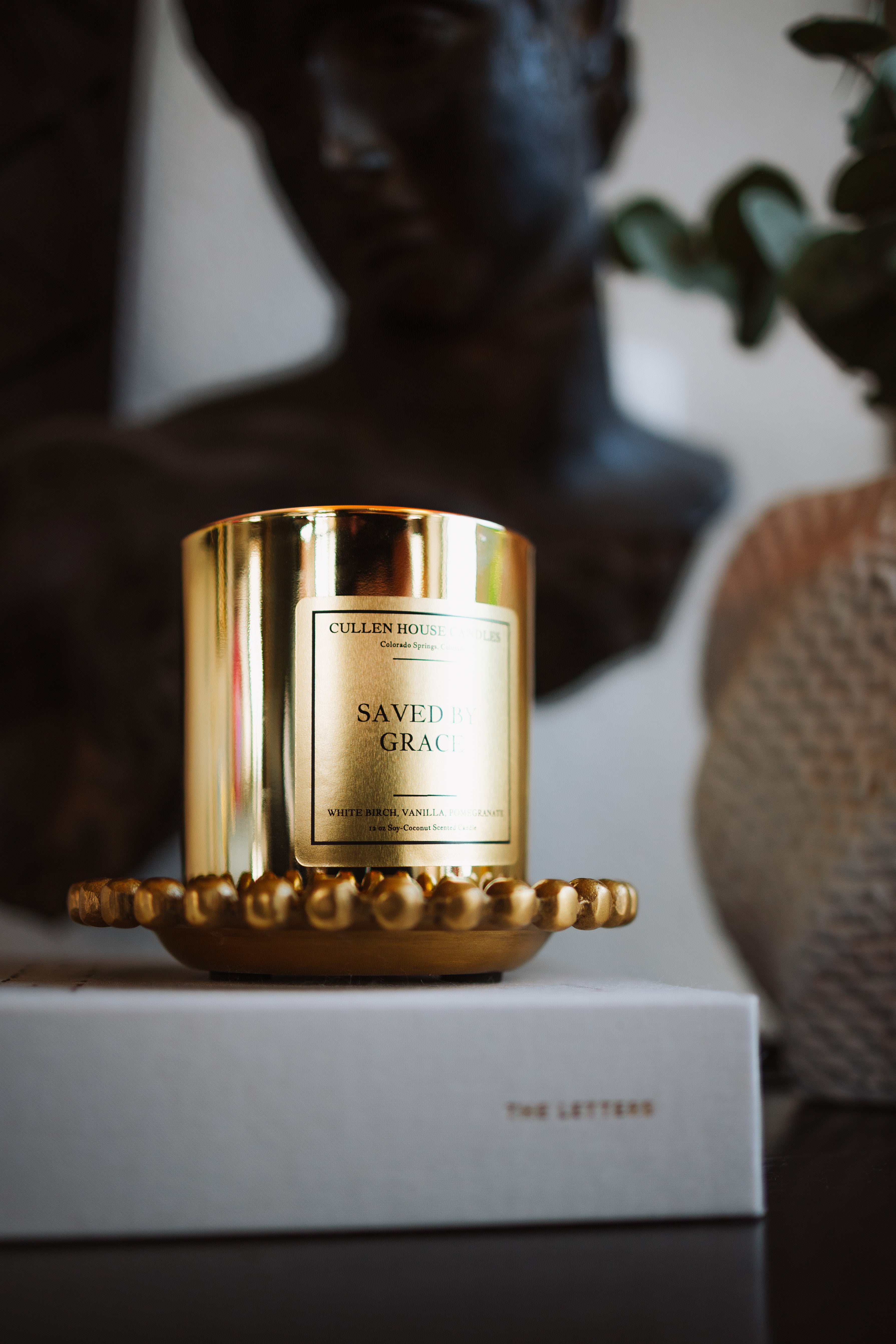 Gold candle with 'Cullen & Co.' branding on a white surface with a blurred background