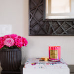 Pink candle and flowers on a table with a decorative mirror in the background