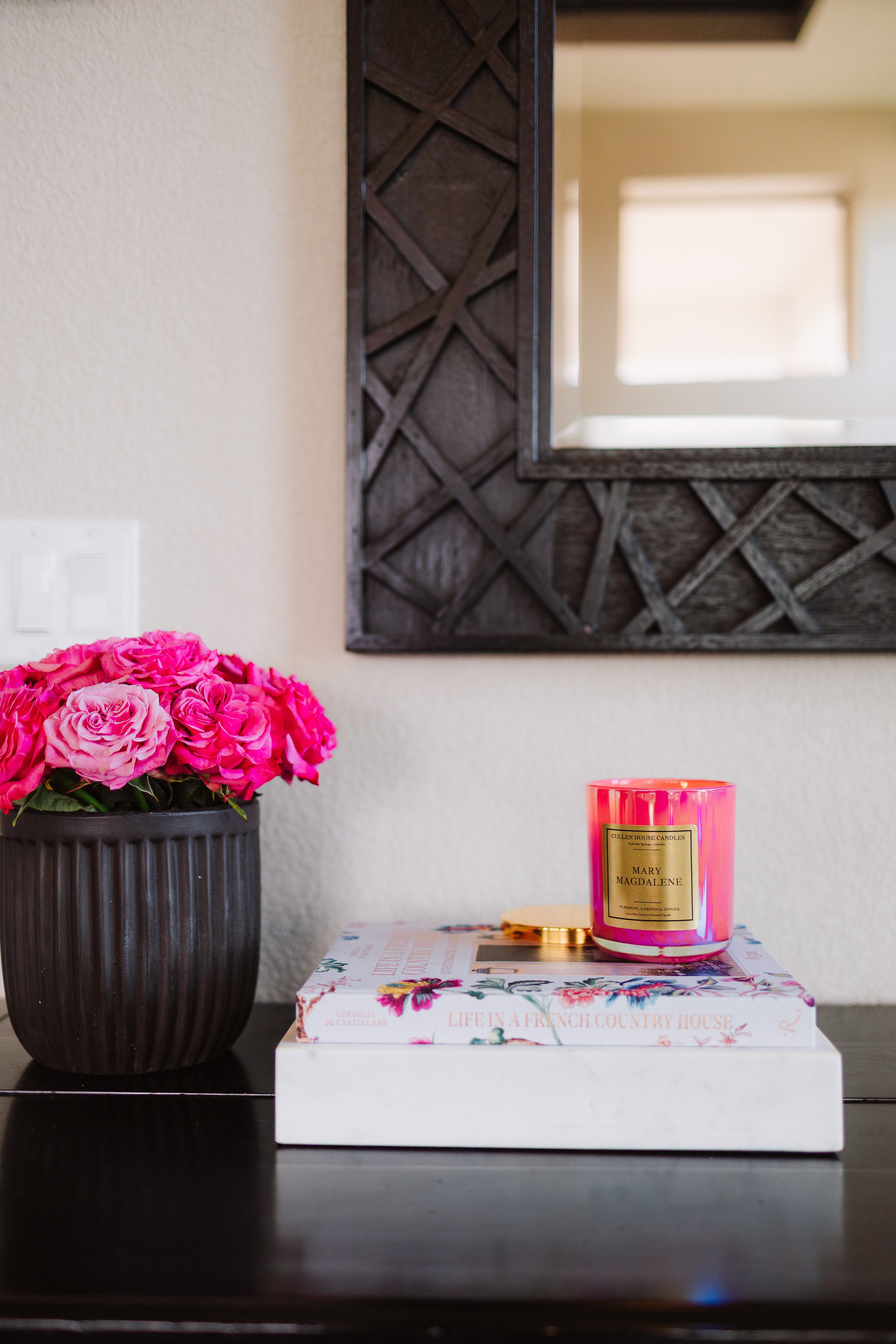 Pink candle and flowers on a table with a decorative mirror in the background