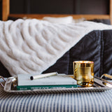 Tray with a book and candle on a bed with striped bedding