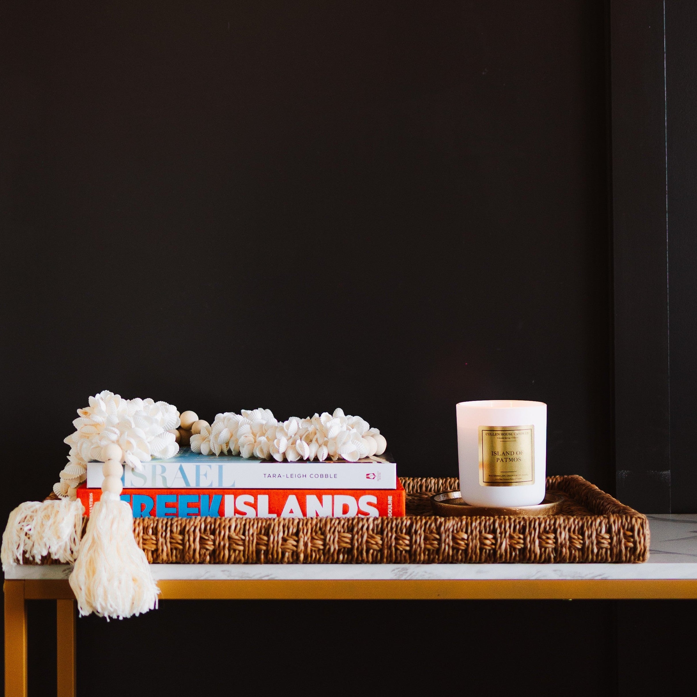Decorative setup with books, a candle, and decorative items on a table against a black background