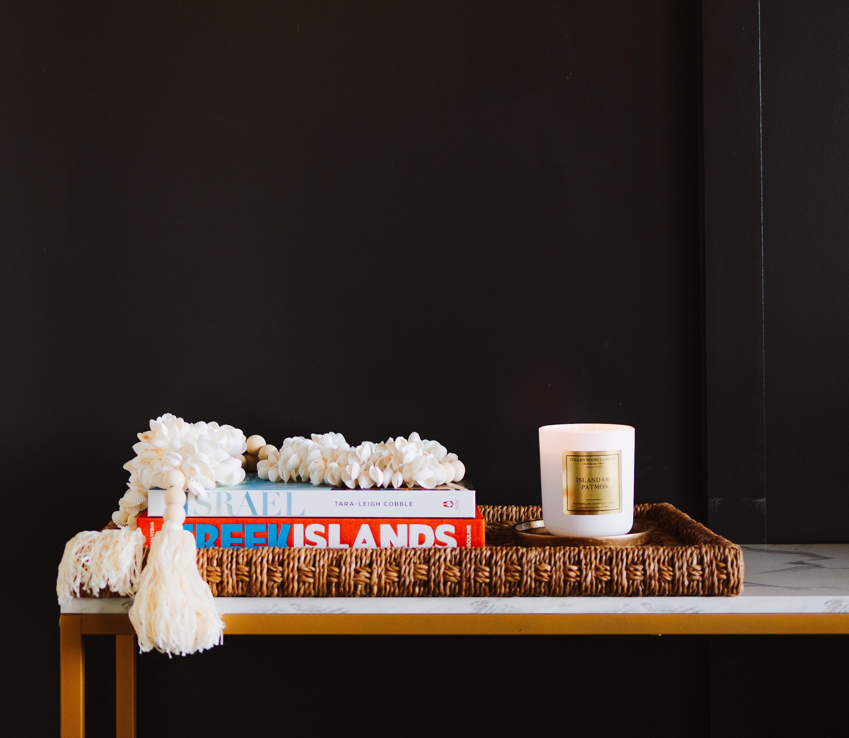 Decorative setup with books, a candle, and decorative items on a table against a black background