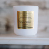 White candle with a gold label on a blurred background
