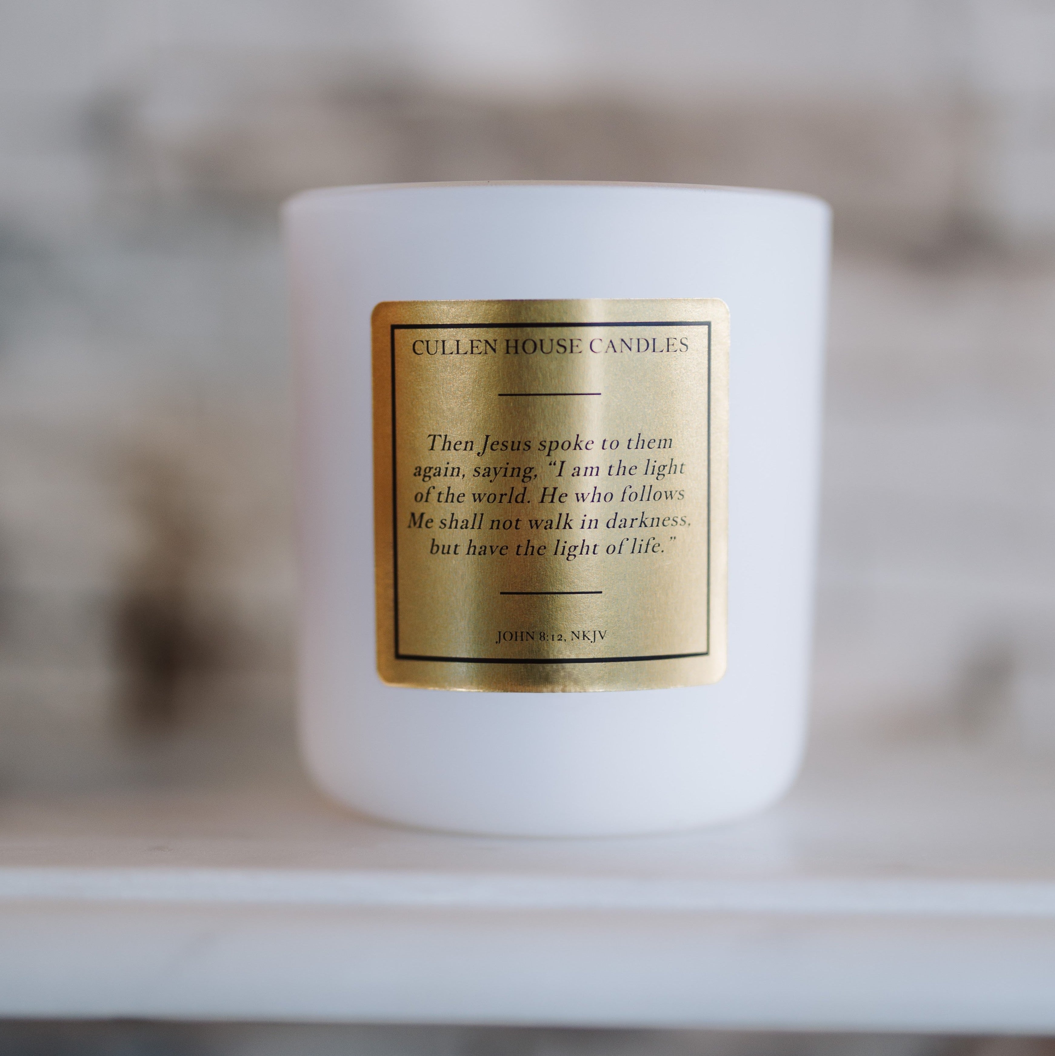 White candle with a gold label on a blurred background