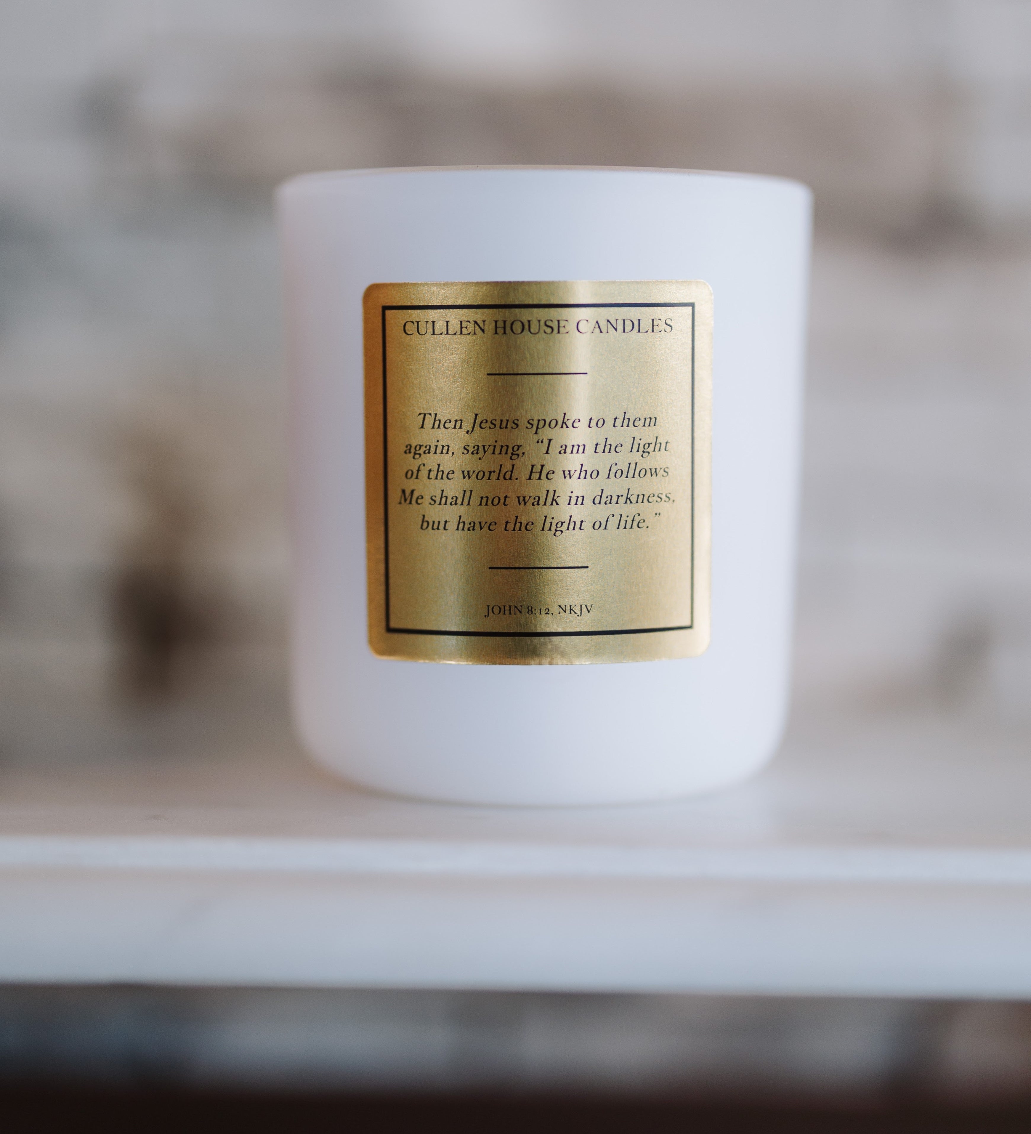 White candle with a gold label on a blurred background