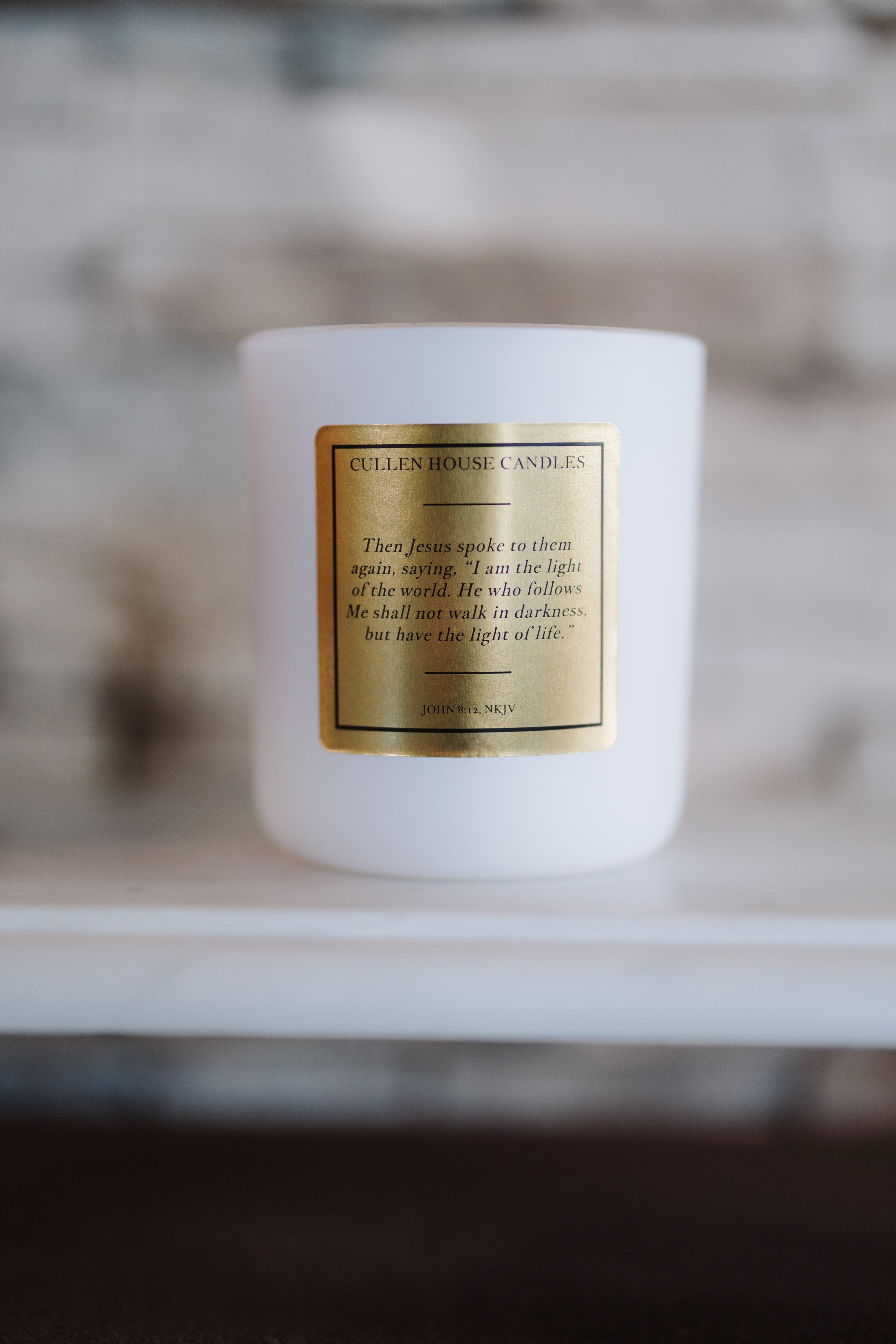 White candle with a gold label on a blurred background