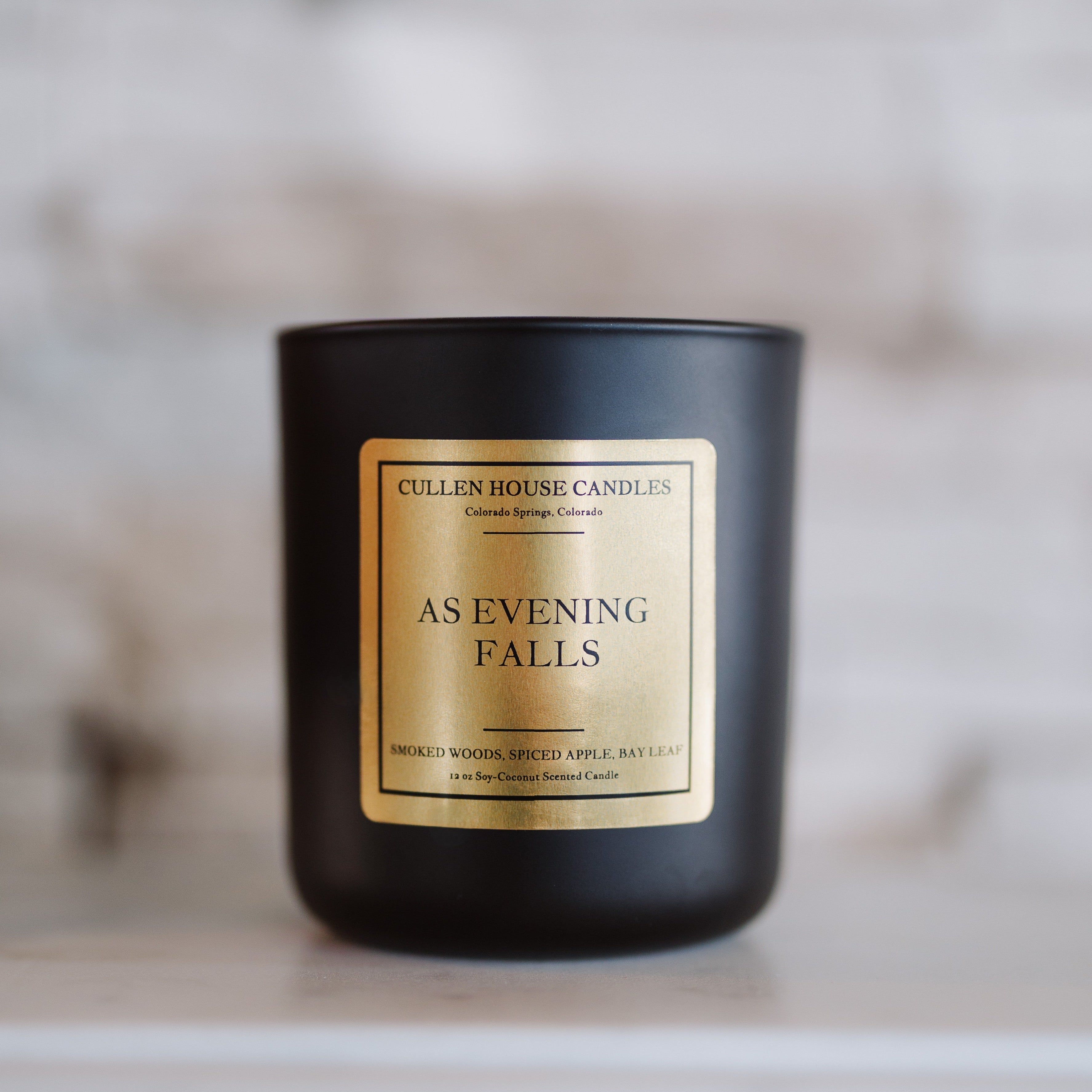 Black candle with a gold label on a marble surface