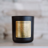 Black candle with a gold label on a marble surface