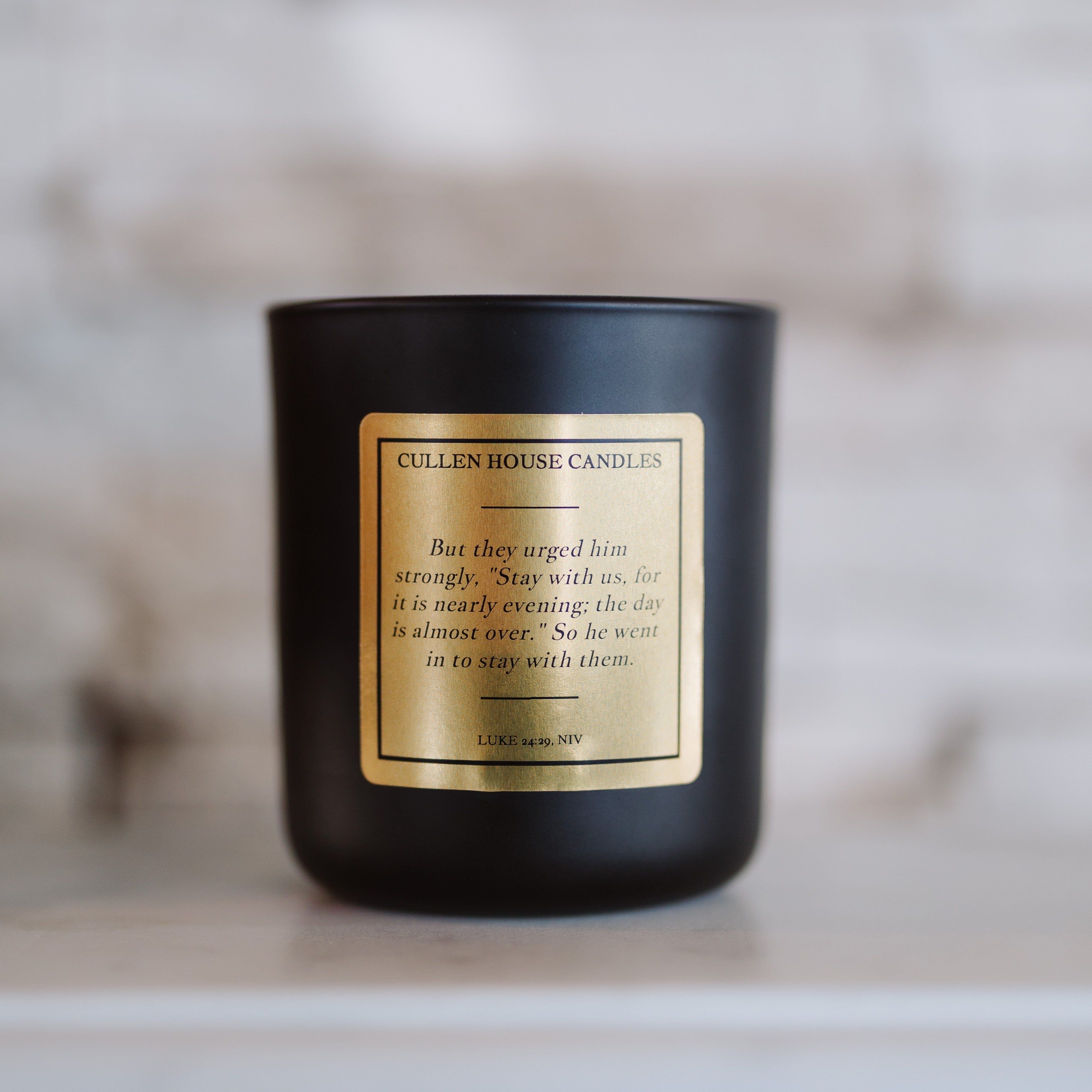 Black candle with a gold label on a marble surface