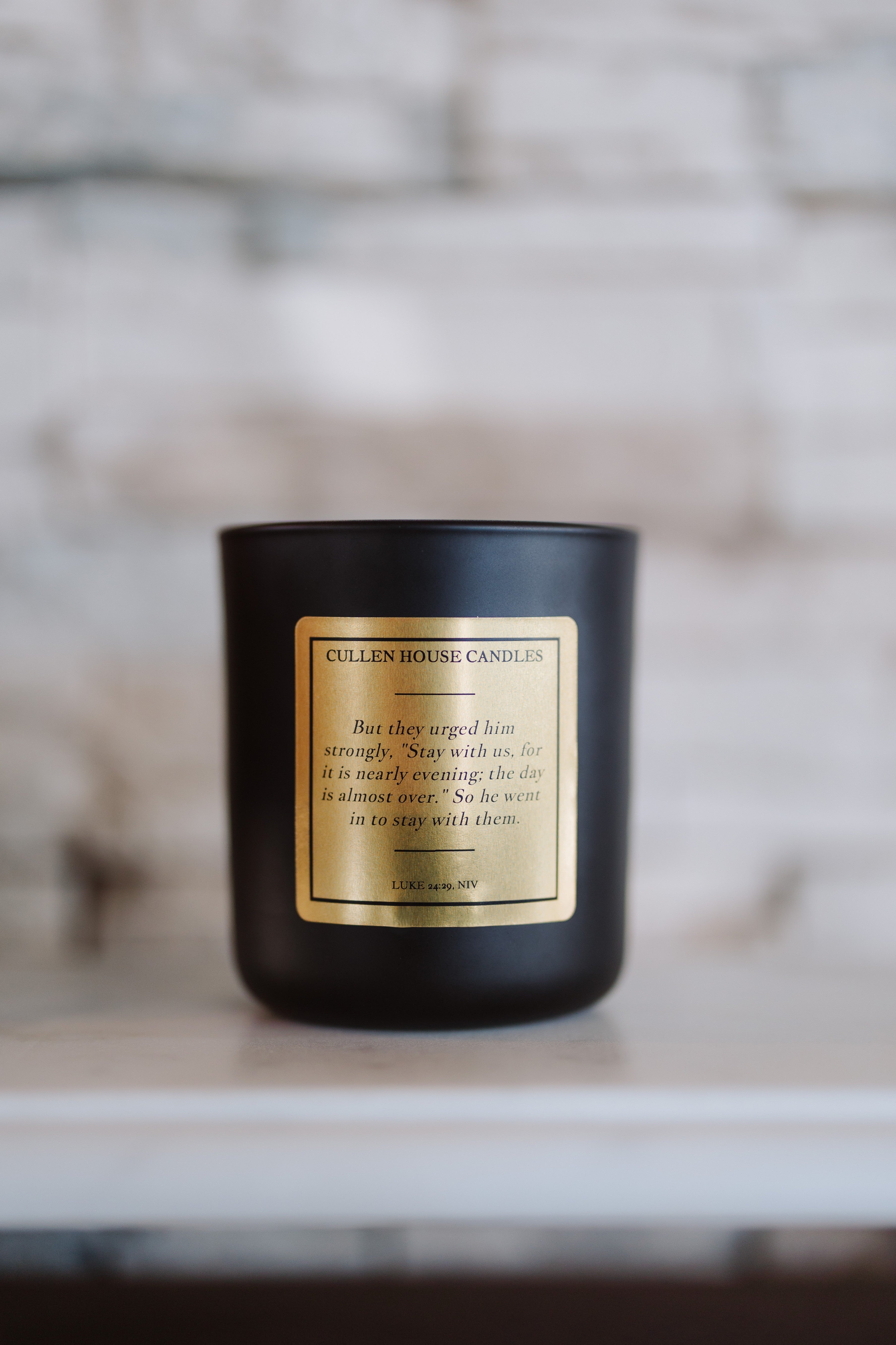 Black candle with a gold label on a marble surface