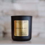 Black candle with a gold label on a white surface