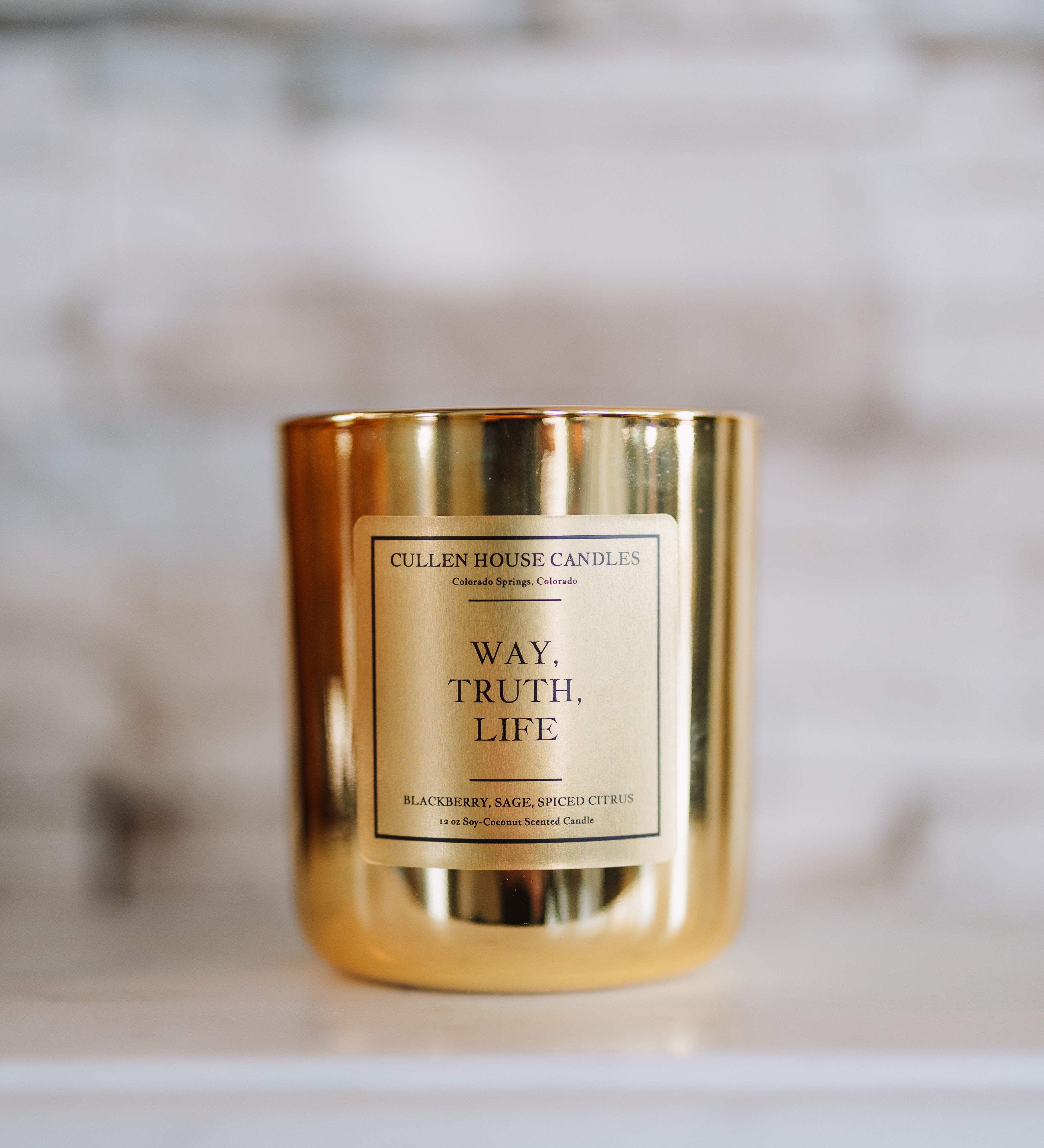 Gold candle with a label on a marble surface