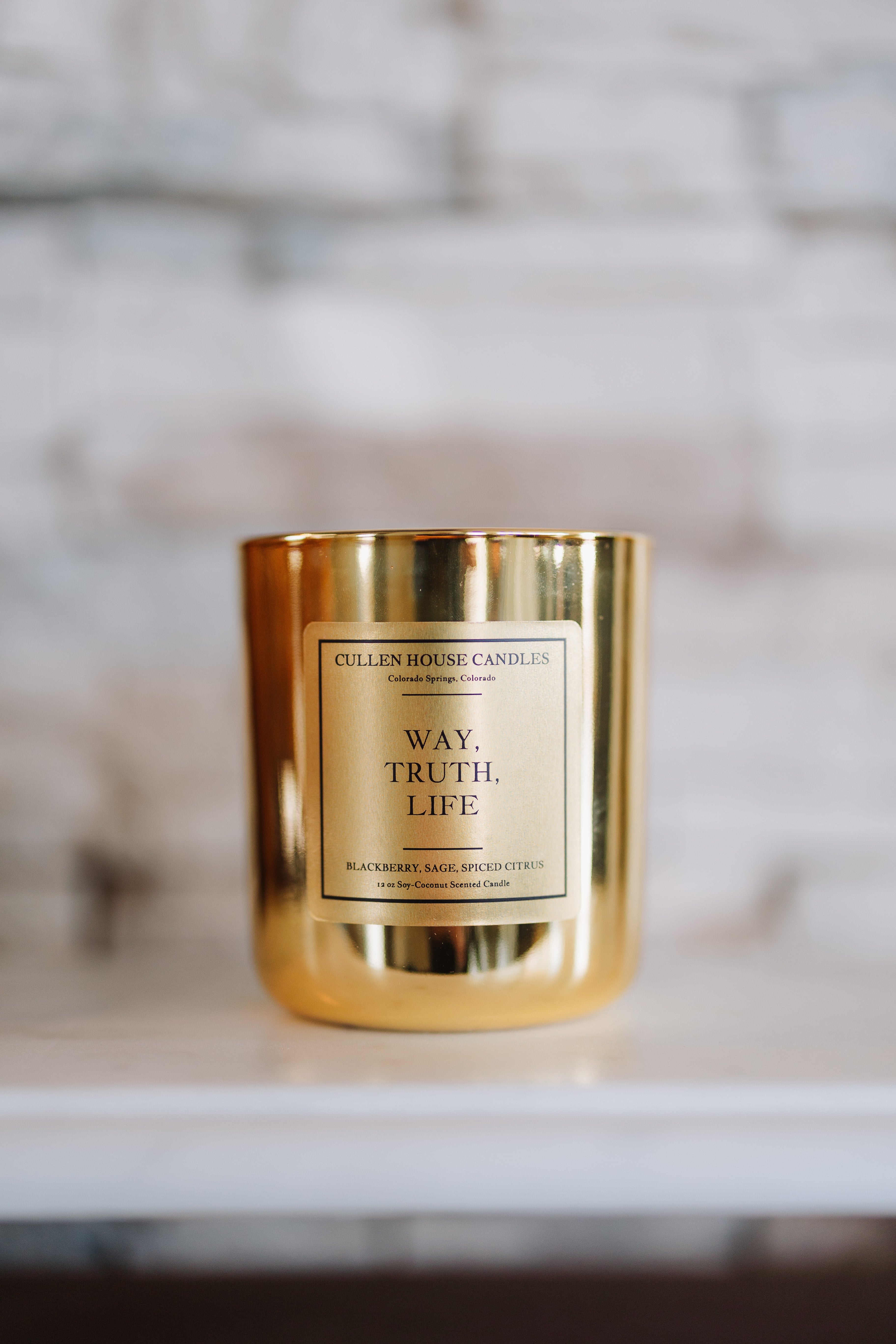 Gold candle with a label on a marble surface
