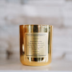 Gold candle with a label on a white surface